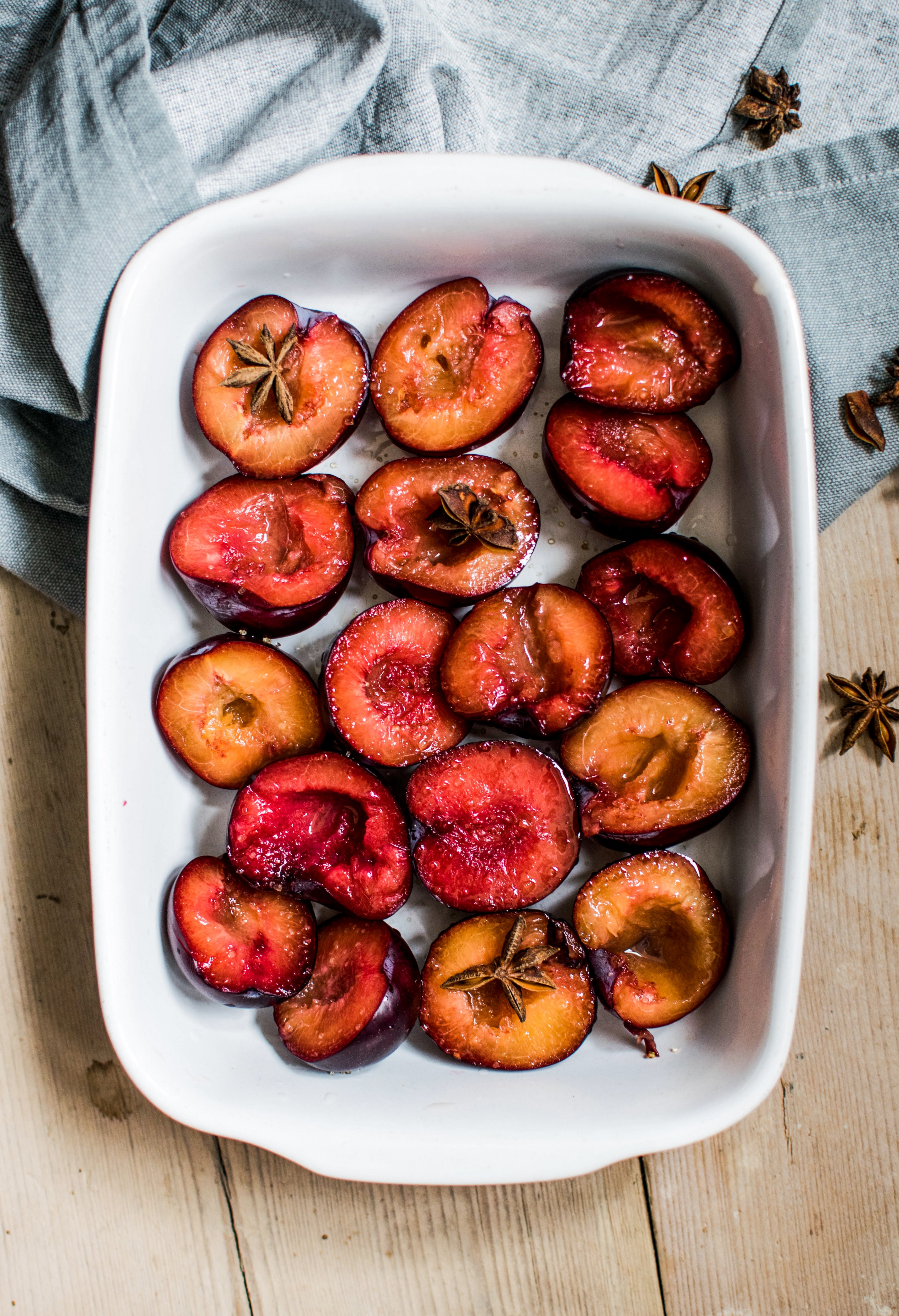 baked plums in a tray on a wooden table, roasted plums 4k, Phone HD Wallpaper