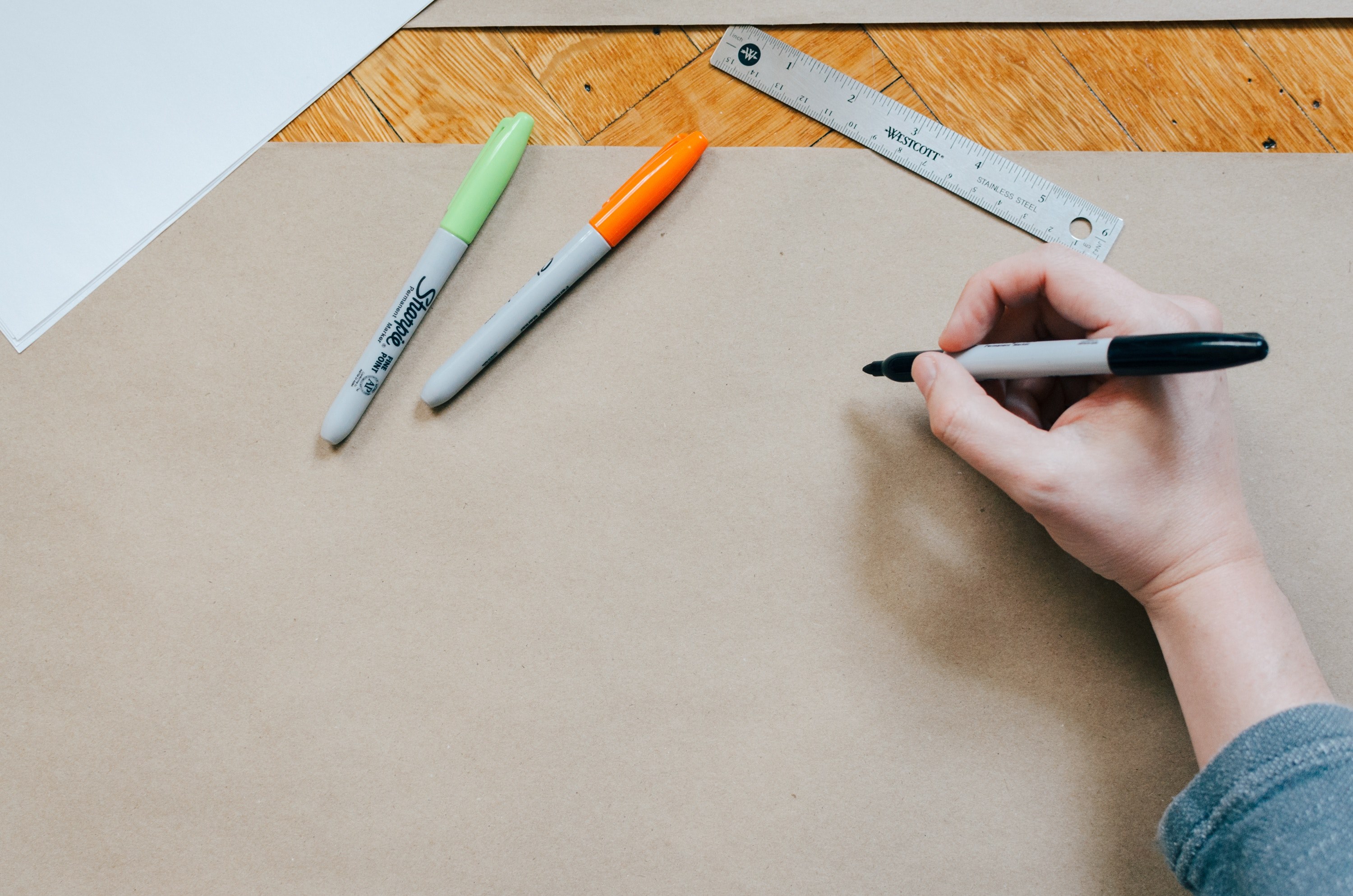 an overhead shot of a persons hand drawing on brown paper with a sharpie, design work 4k, HD Wallpaper