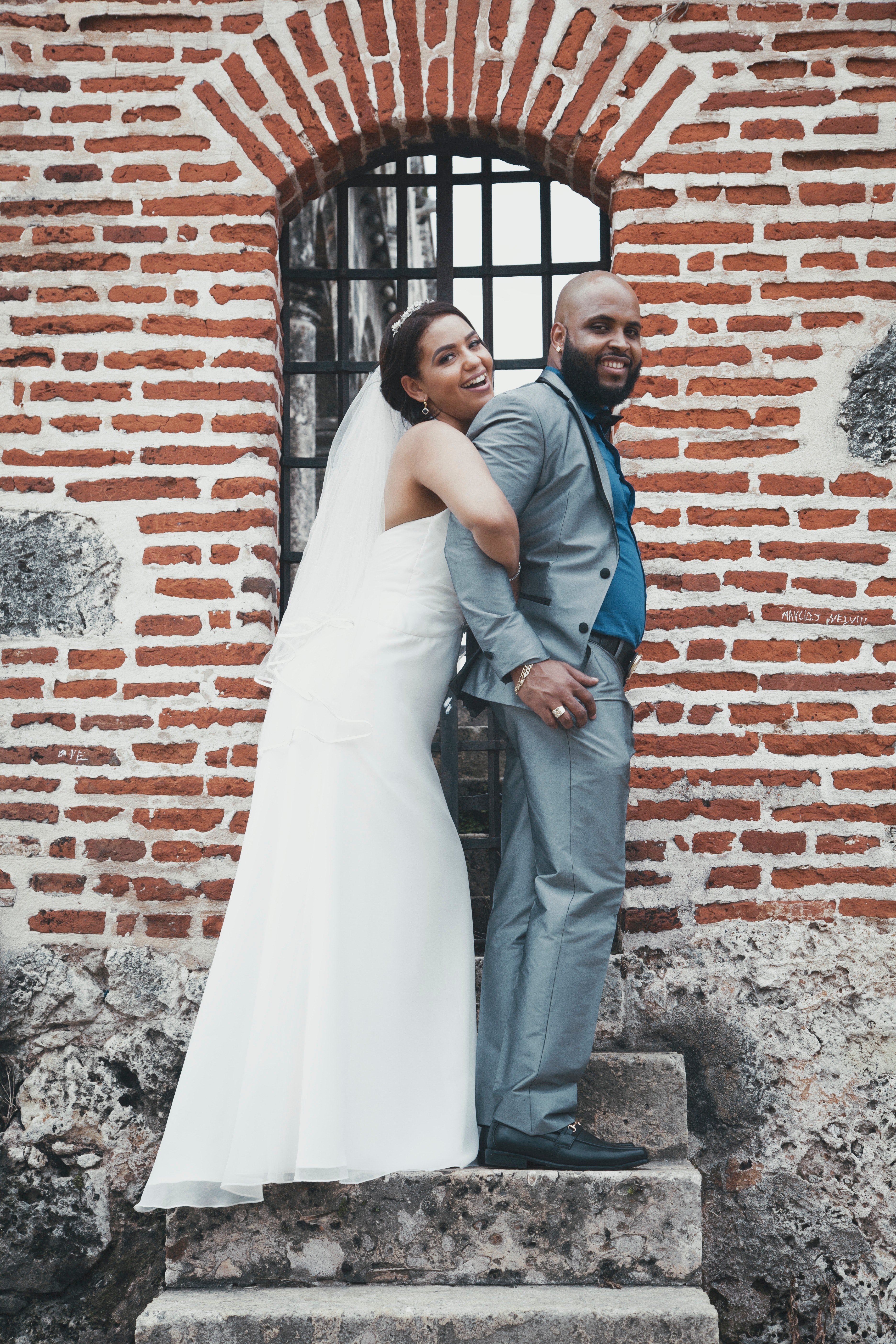 a bride holding a grooms arms from behind on concrete steps by a brick wall, bride wrestles groom 4k, Phone HD Wallpaper