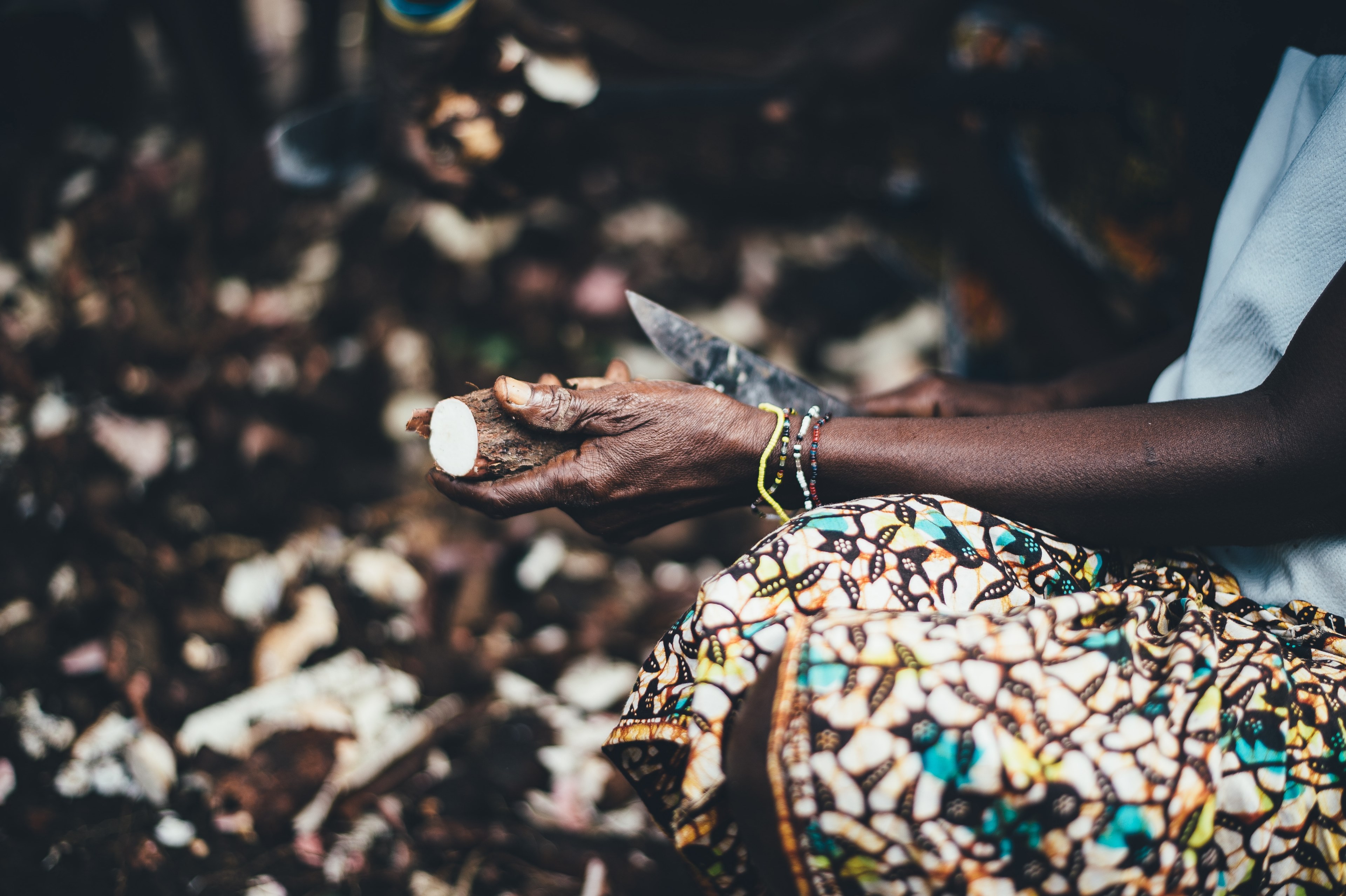 a woman wearing a patterned shirt peeling food in sierra leone, carving food 4k, HD Wallpaper