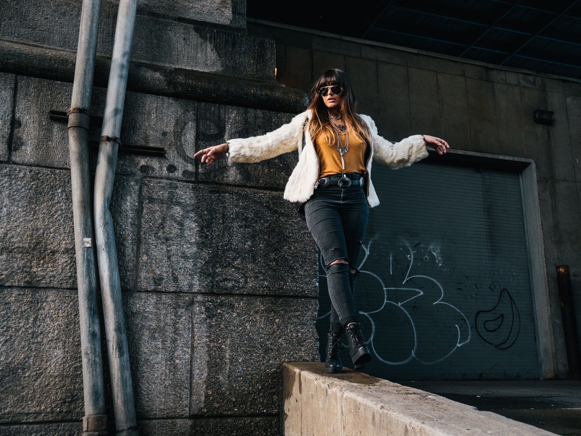 a woman wearing ripped jeans combat boots and a fur jacket walking on a wall in chinatown, woman posing by drainpipe 4k, HD Wallpaper