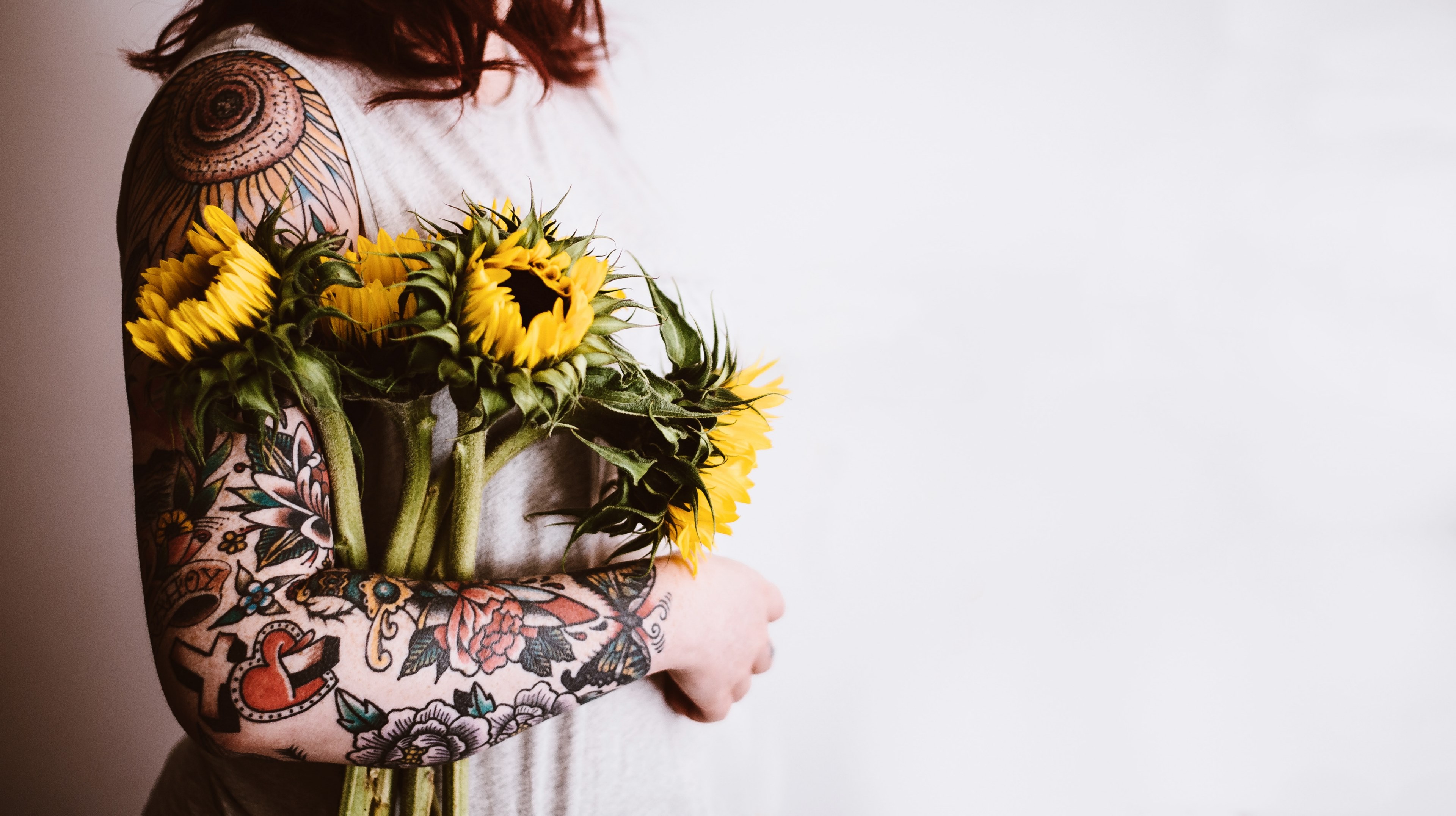 portrait shot of woman with tattoo sleeve holding bunch of wilting sunflowers against white background, holding sunflowers 4k, HD Wallpaper