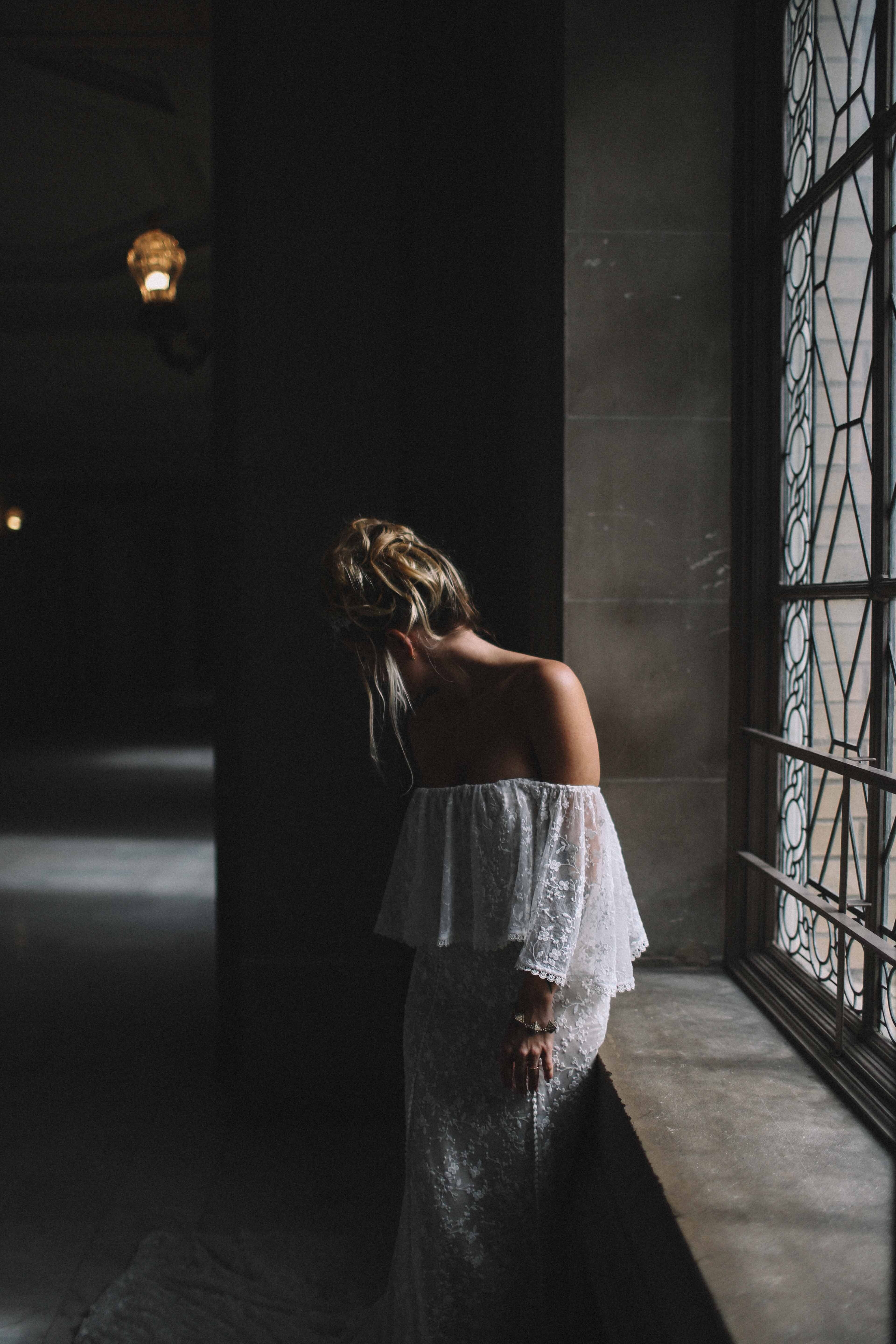 a bride in a lacy off the shoulder top lowers her head aside a stained glass window, bride in off the shoulder dress 4k, Phone HD Wallpaper