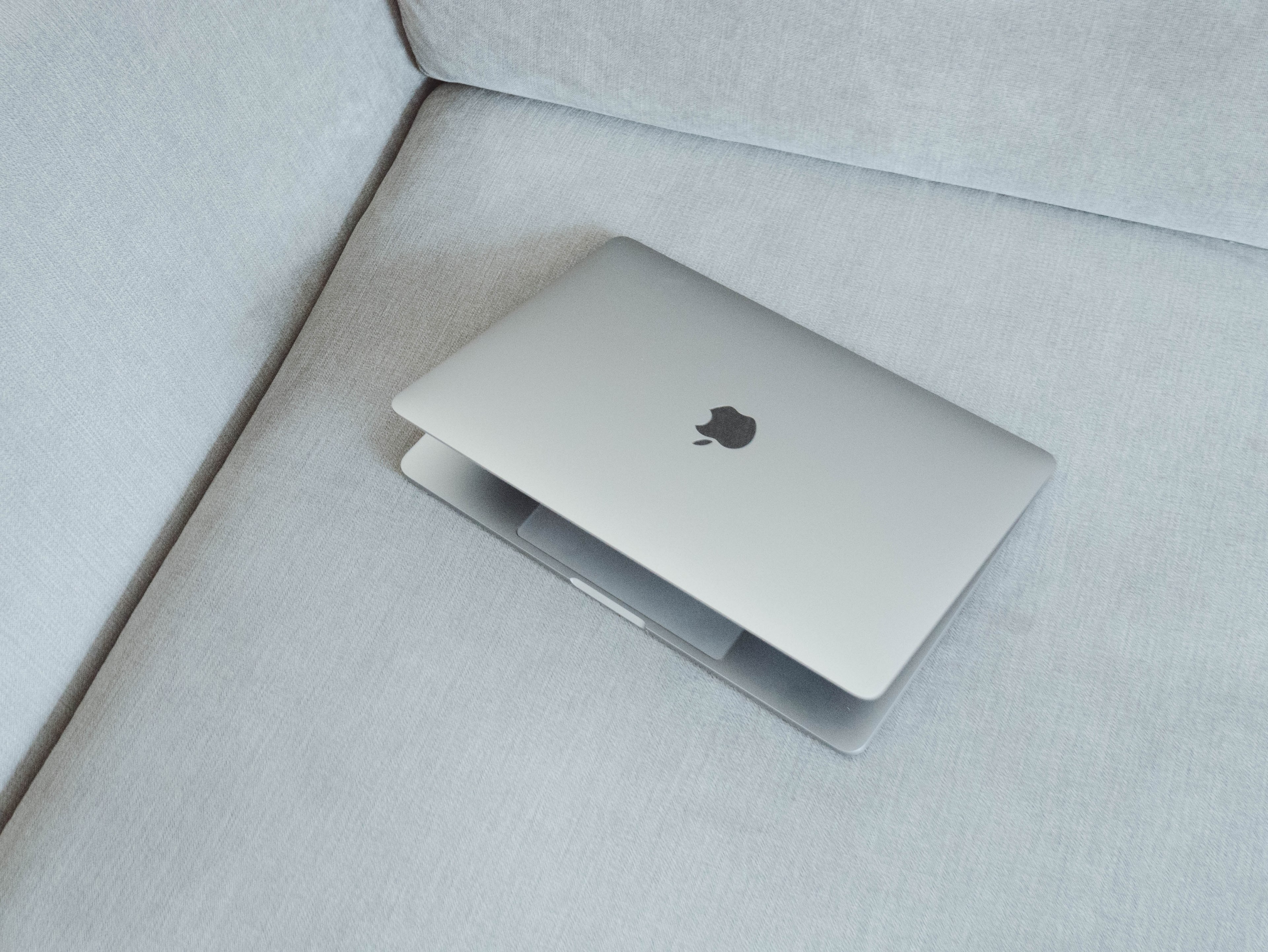 a macbook slightly open resting on a gray couch, chilled days at home_ 4k, HD Wallpaper