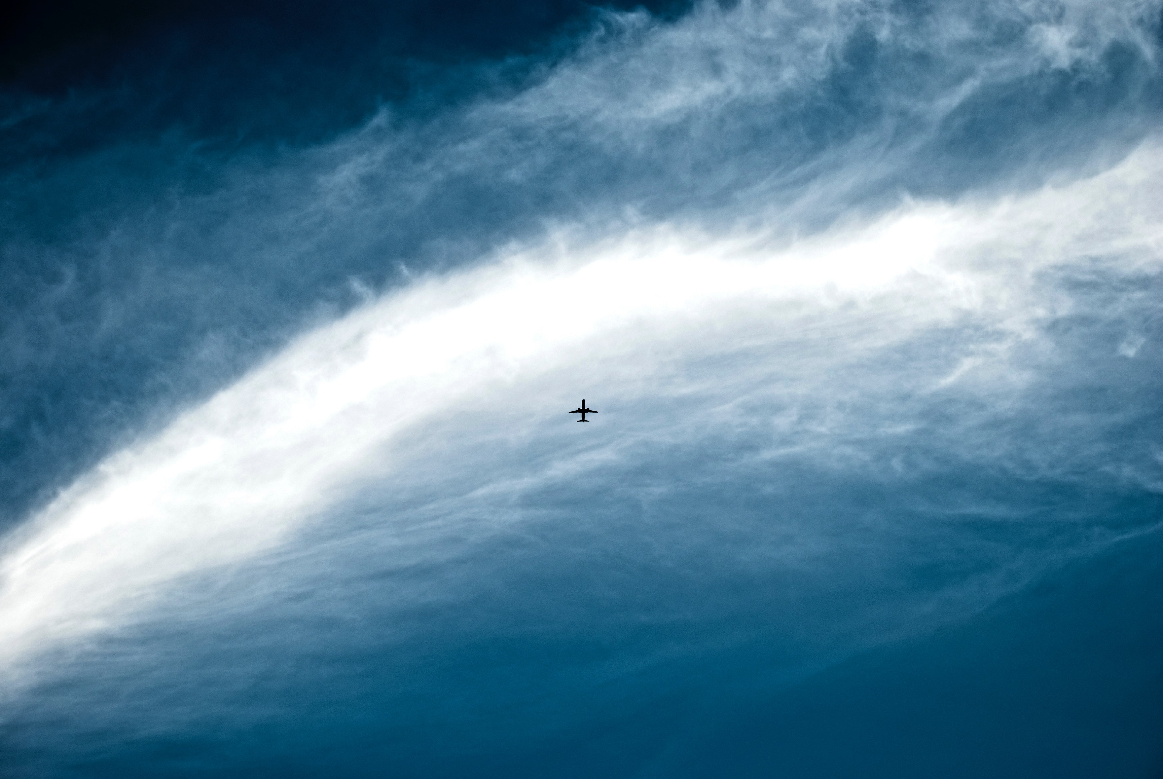 a small black silhouette of a plane on a cloudy sky, plane silhouette among clouds 4k, HD Wallpaper