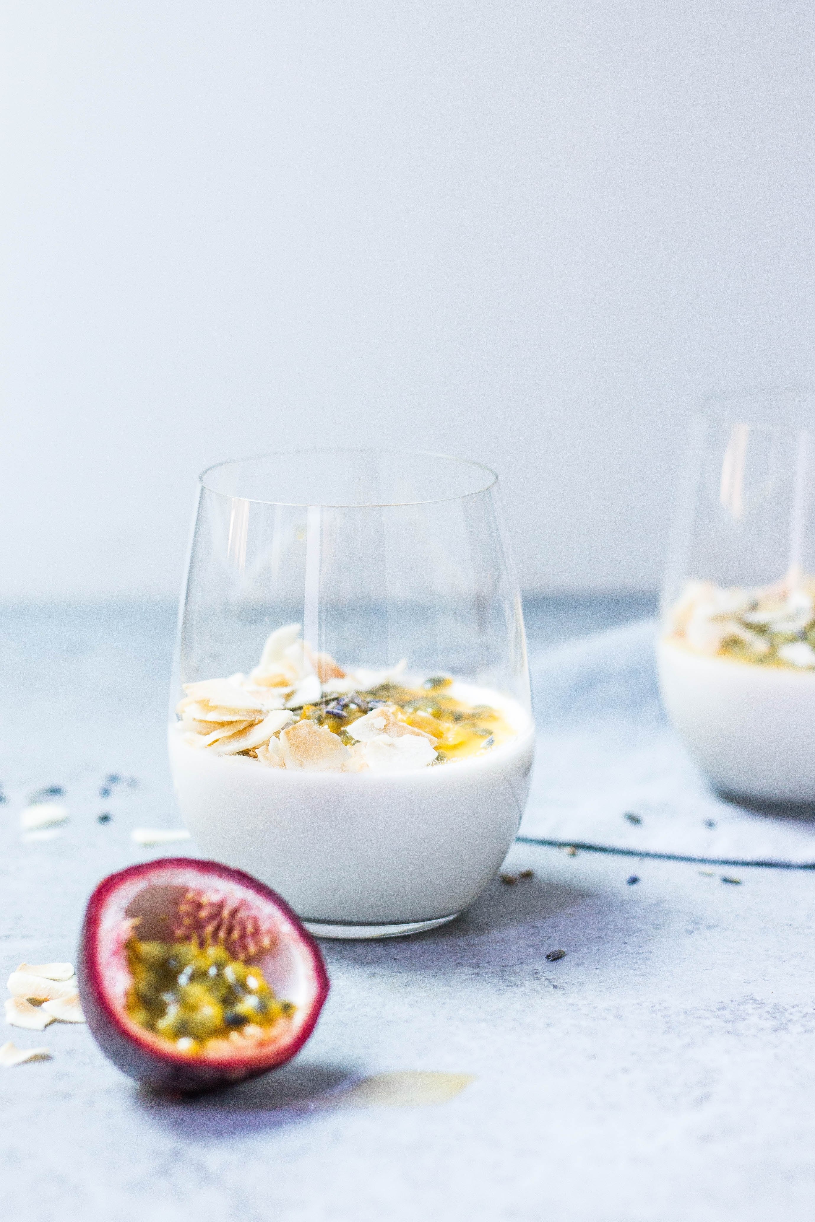 a cut half of a passion fruit next to glasses with yogurt with dried fruit, coconut amp passion fruit panna cotta 4k, Phone HD Wallpaper