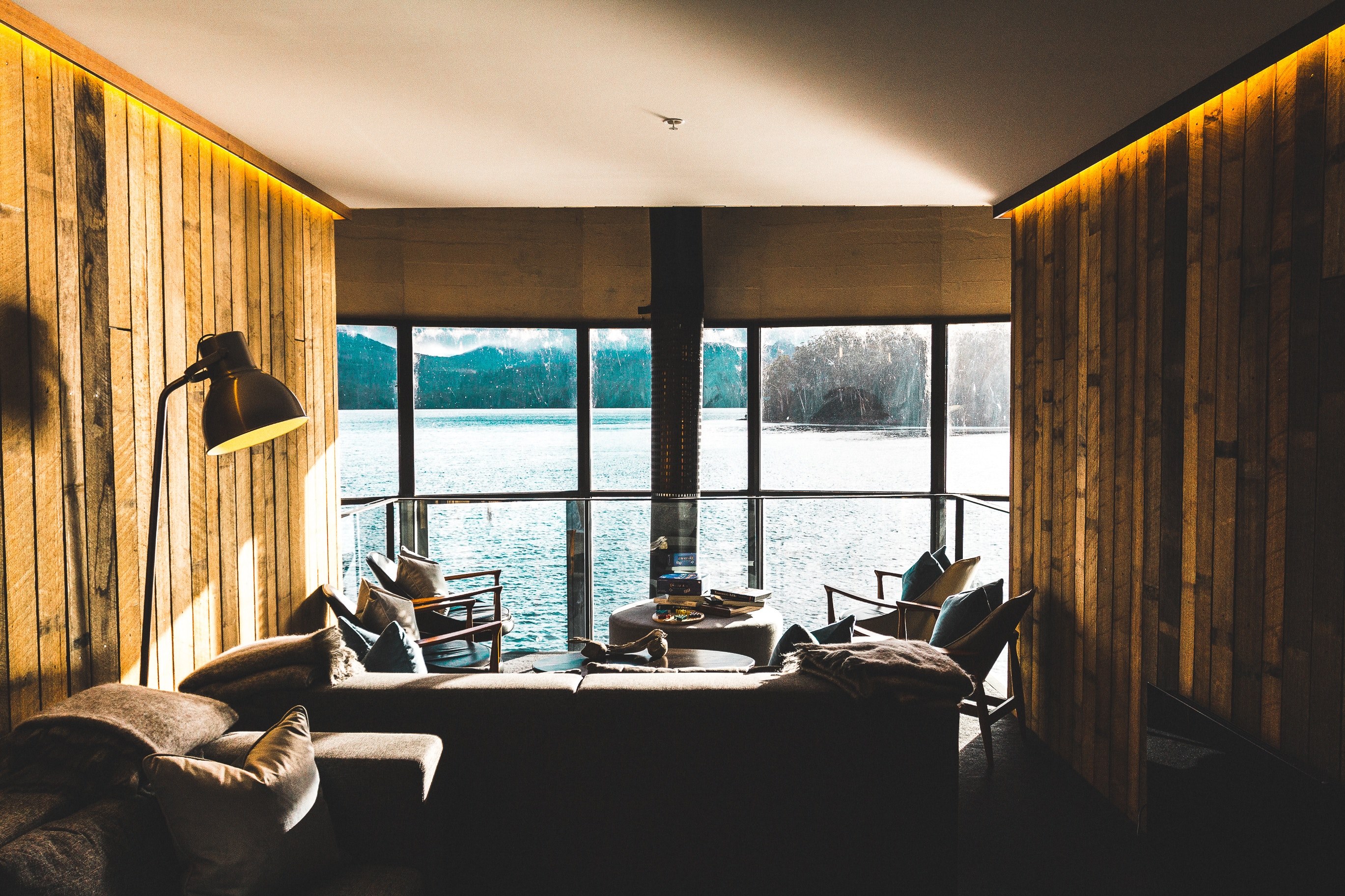 interior of waterfront room with dark couches chairs fireplace and large window, lake st clair 4k, HD Wallpaper