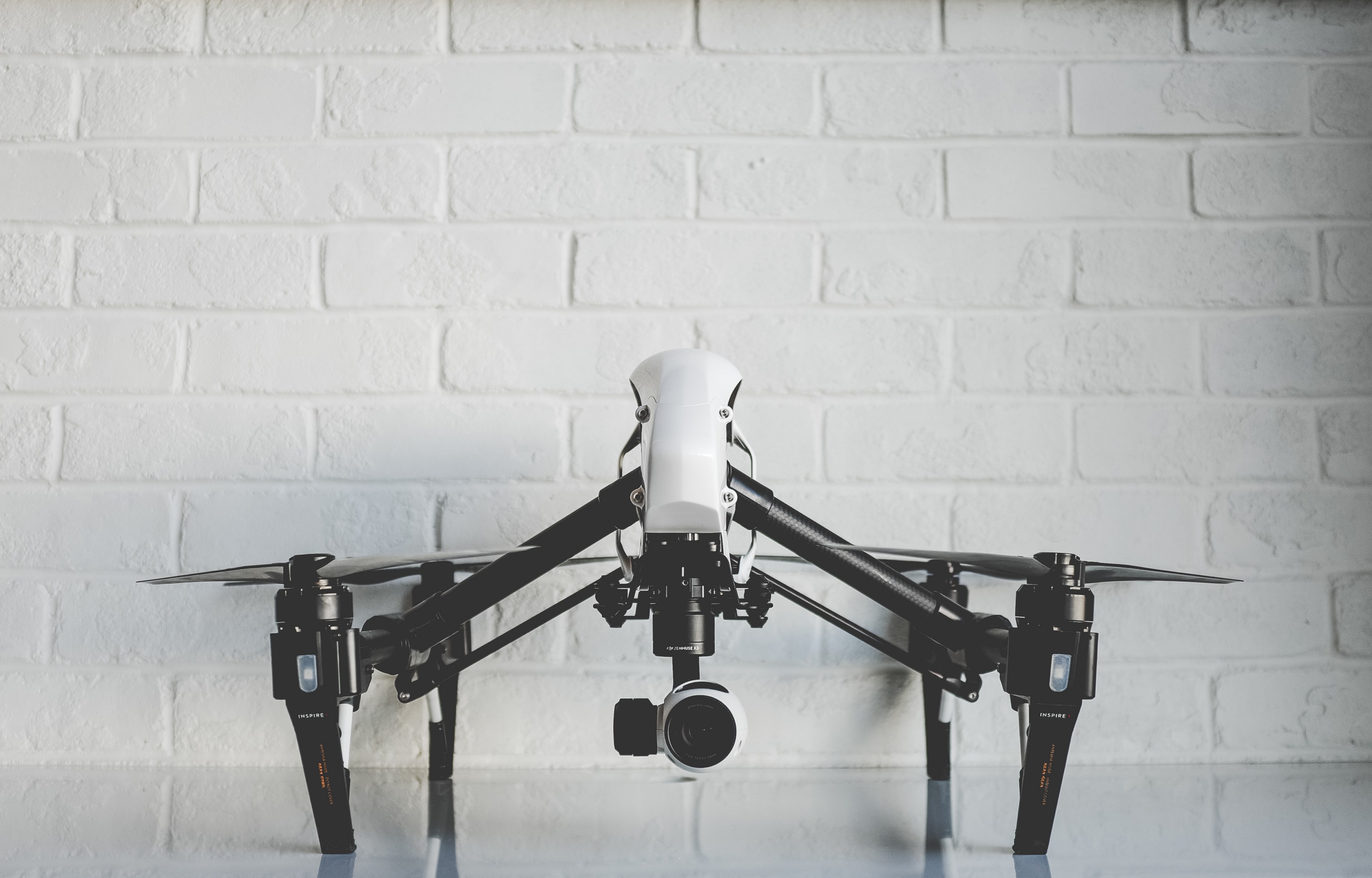 white drone resting on a shiny white surface in front of a white brick wall, drone in an office 4k, HD Wallpaper