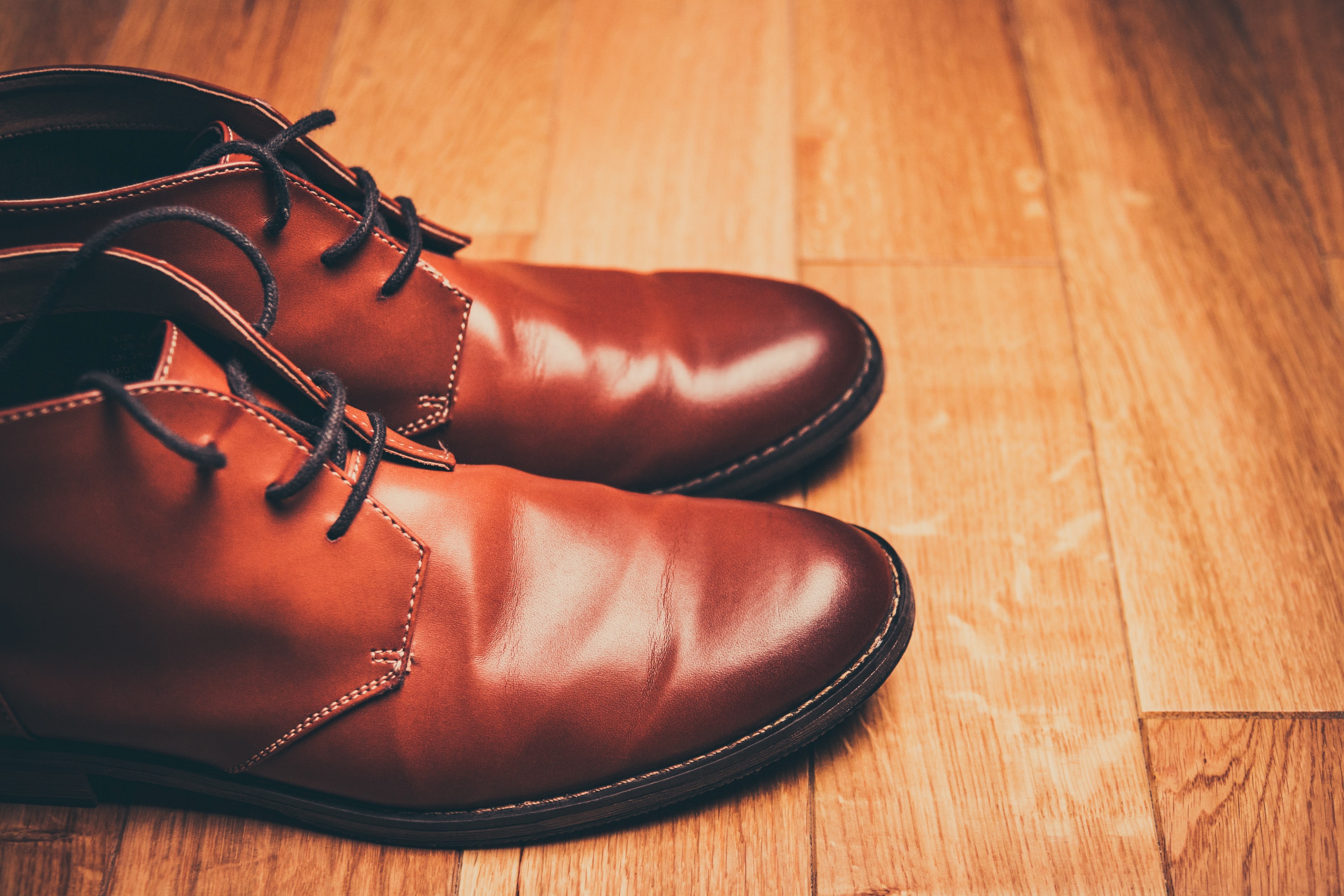 a pair of brown leather boots with the shoestrings tucked in on wooden flooring, brown leather boots on a wood floor 4k, HD Wallpaper