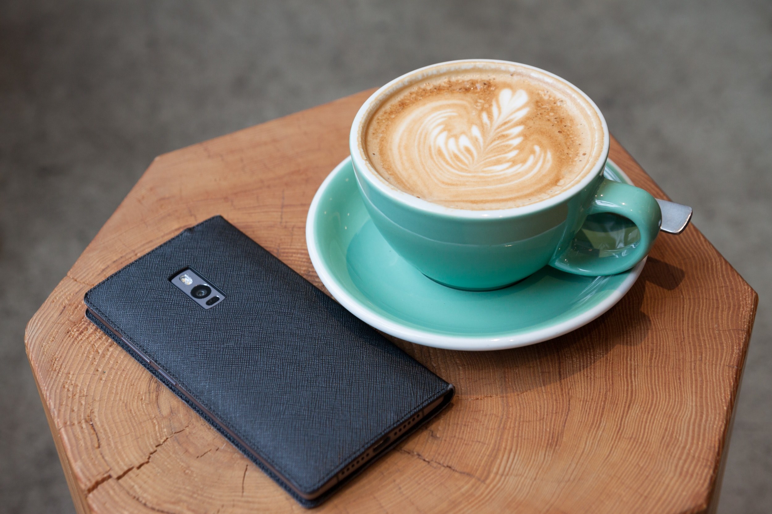 a smartphone on a wooden surface next to a cup of coffee with latte art, quality time 4k, HD Wallpaper
