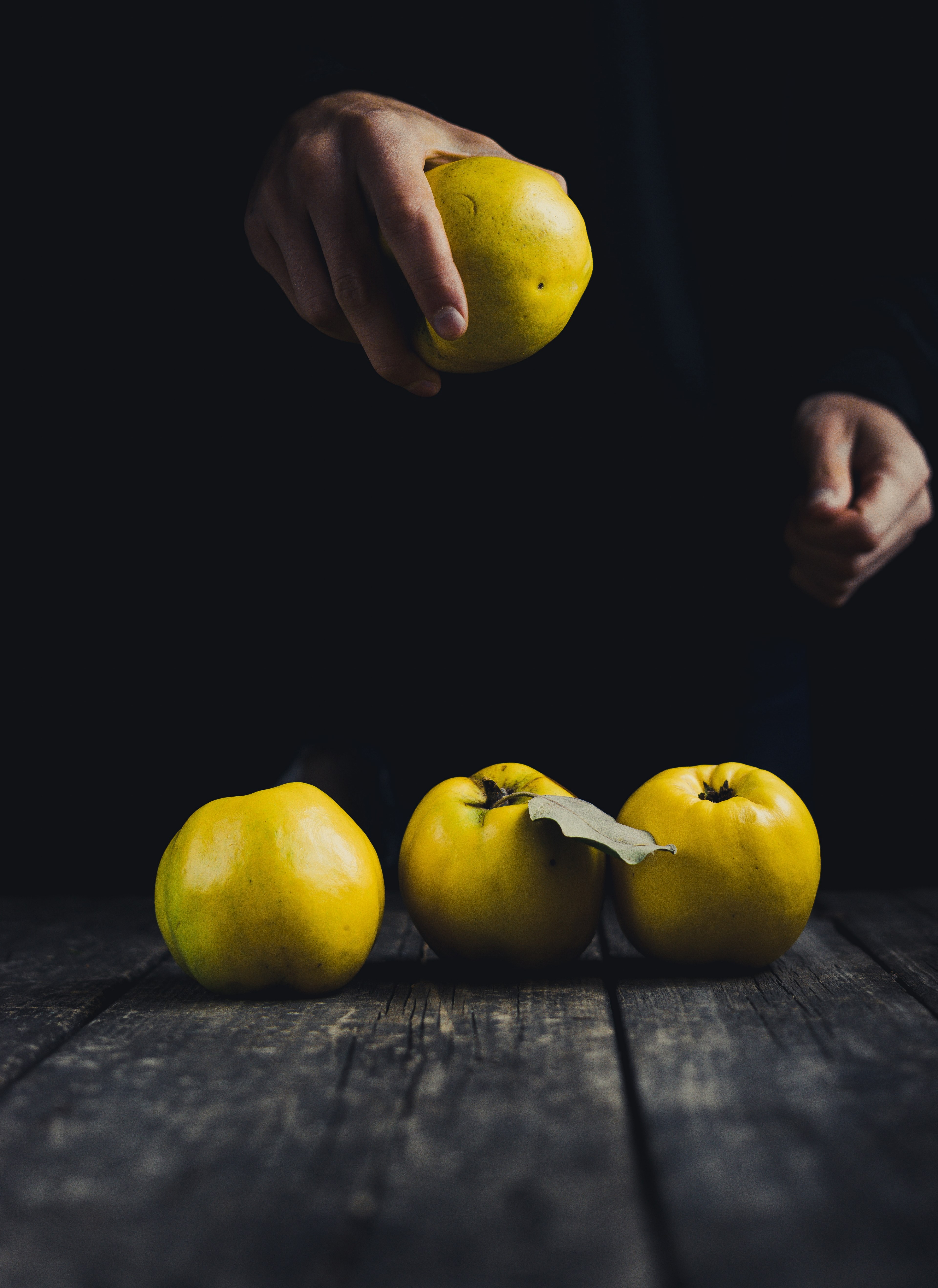 quince in hand and on dark wooden background 4k, Phone HD Wallpaper