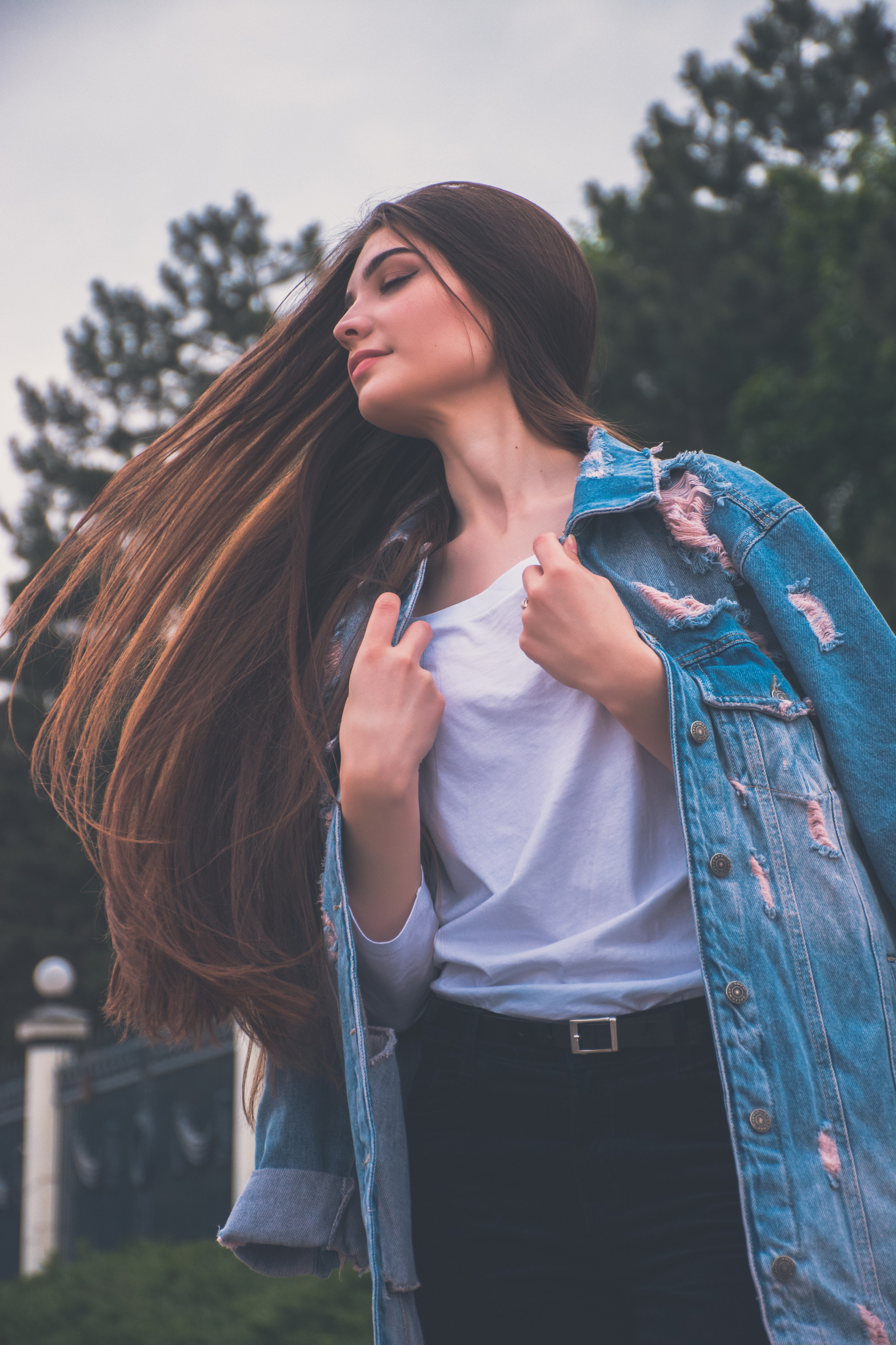a woman in a jean coat whips her long brown hair to the side outdoors, magdalena 4 4k, Phone HD Wallpaper