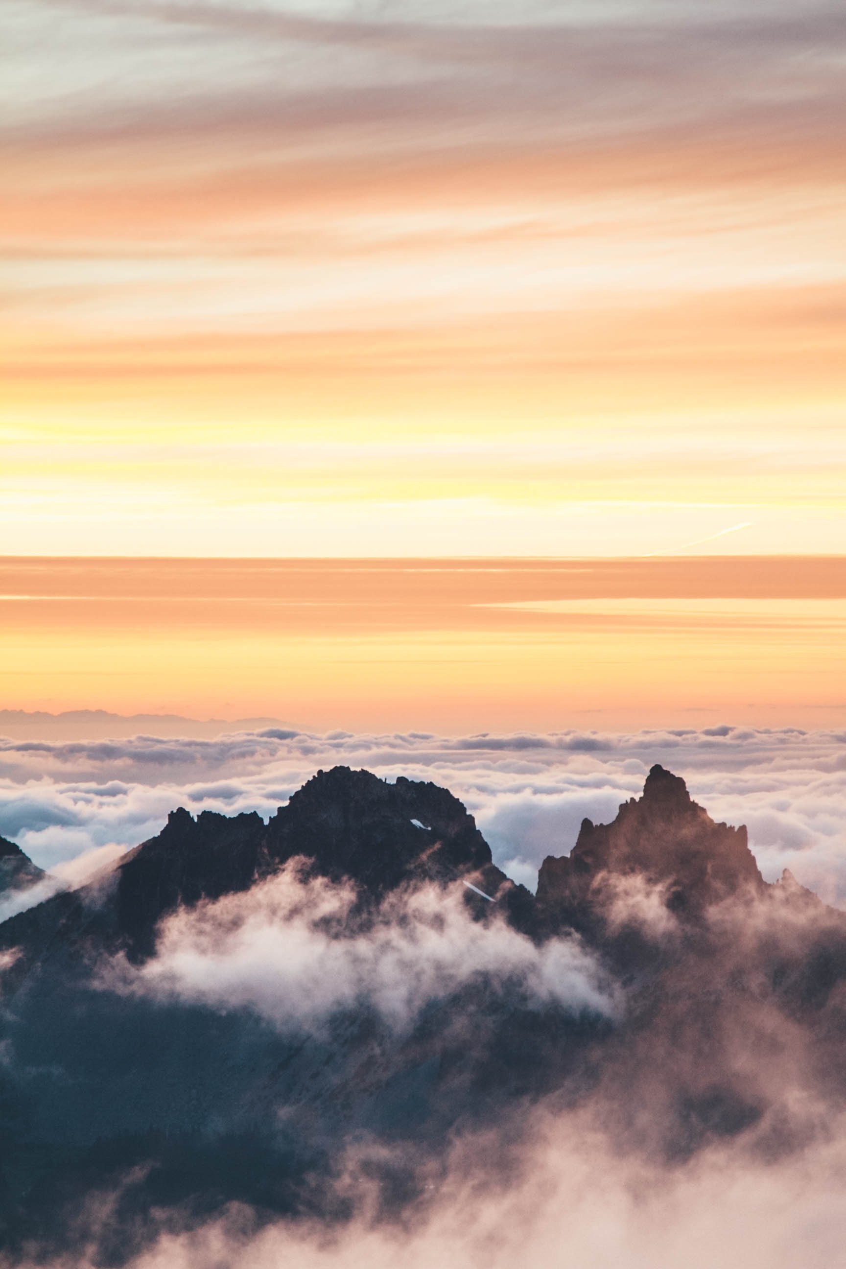jagged mountain peaks emerge from a sea of clouds during sunset, sun sets over cloud shrouded peaks 4k, Phone HD Wallpaper