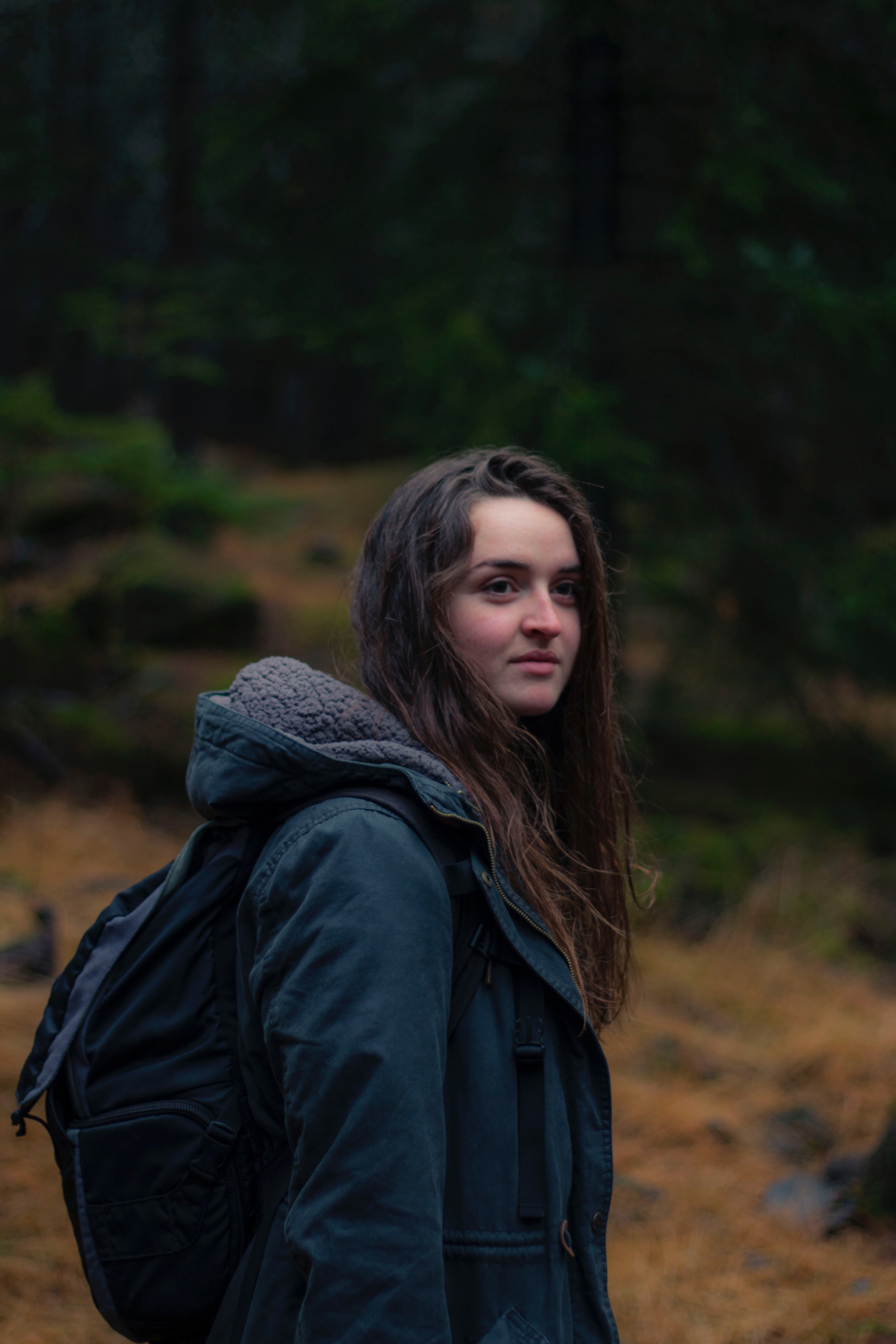 a woman in a hooded coat and backpack looks to the side outdoors in reykjavk, reykjavik forest 4k, Phone HD Wallpaper