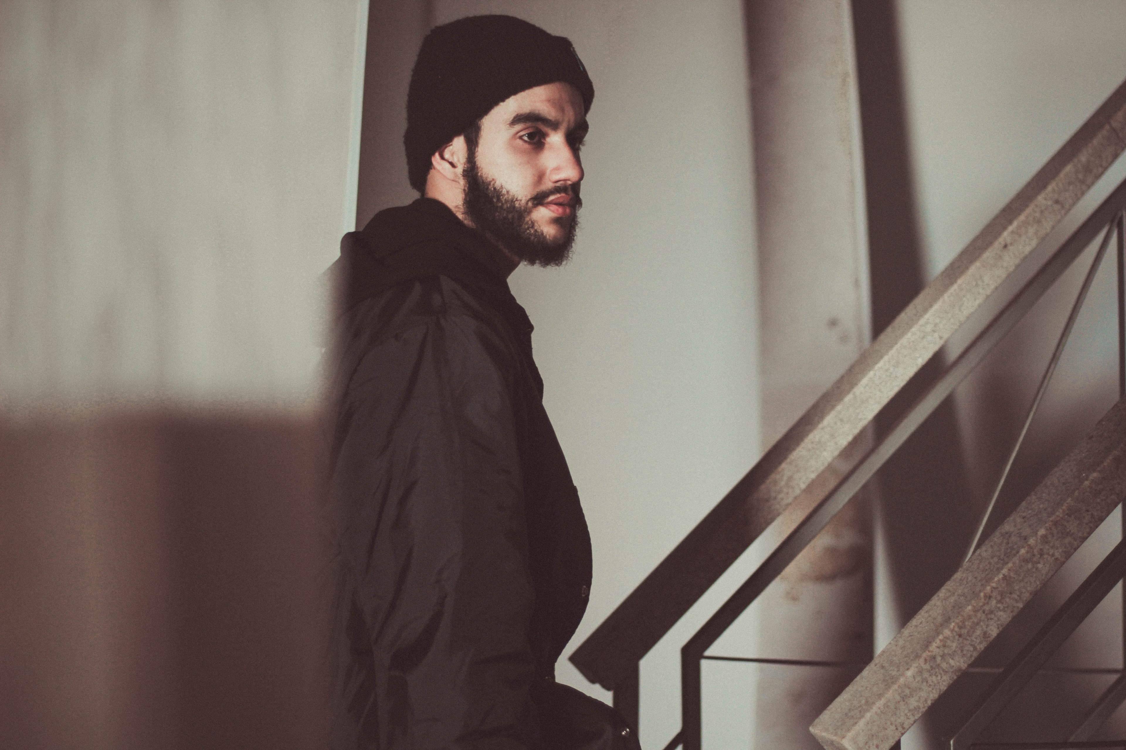 man with a beard wearing a hat walking up an industrial staircase, beard and beanie 4k, HD Wallpaper