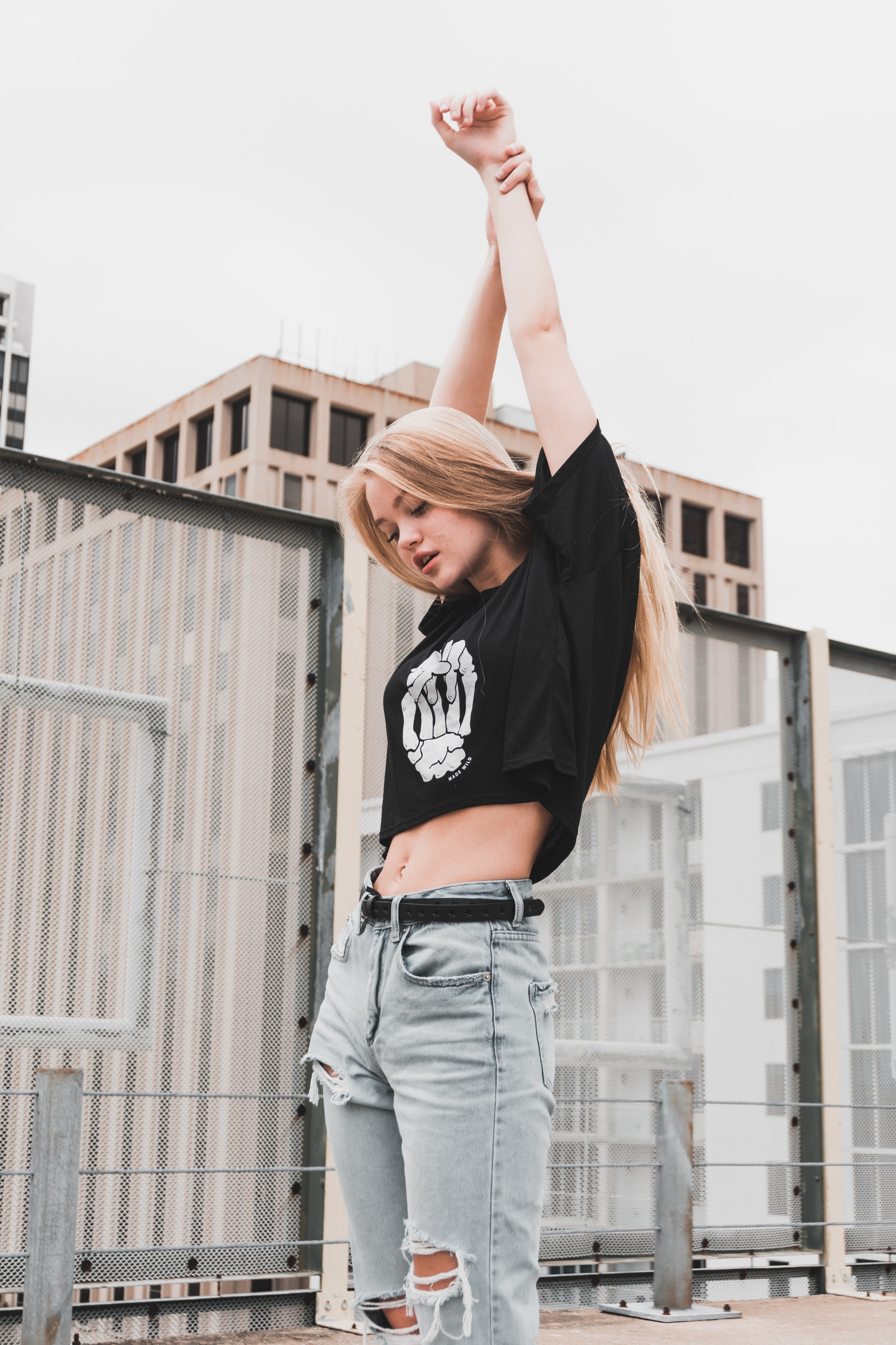 woman in ripped jeans and a skull shirt stretches her arms, stretching her arms 4k, Phone HD Wallpaper