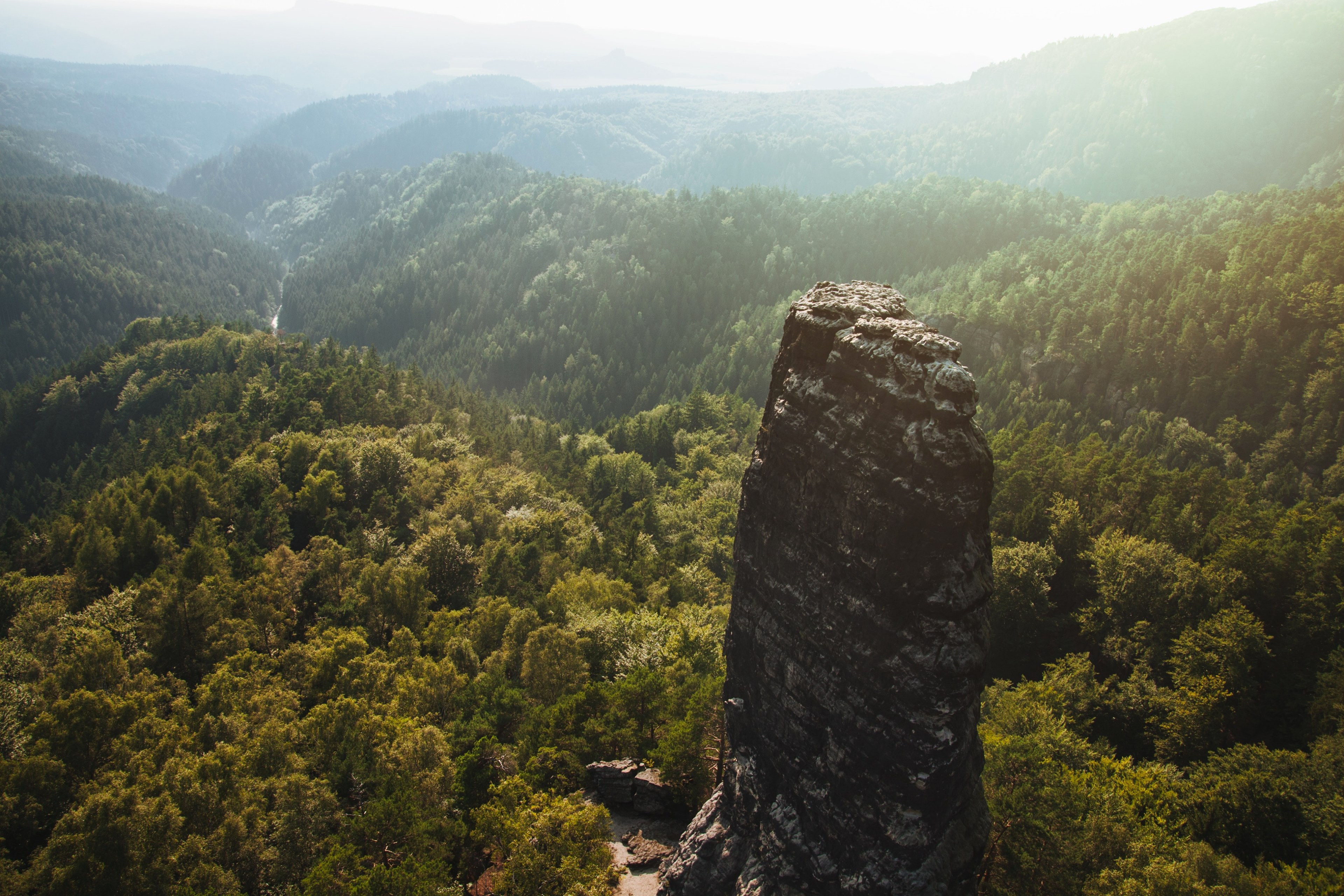 sun shines over a lush forest landscape with a tall rock formation, hensko 4k, HD Wallpaper
