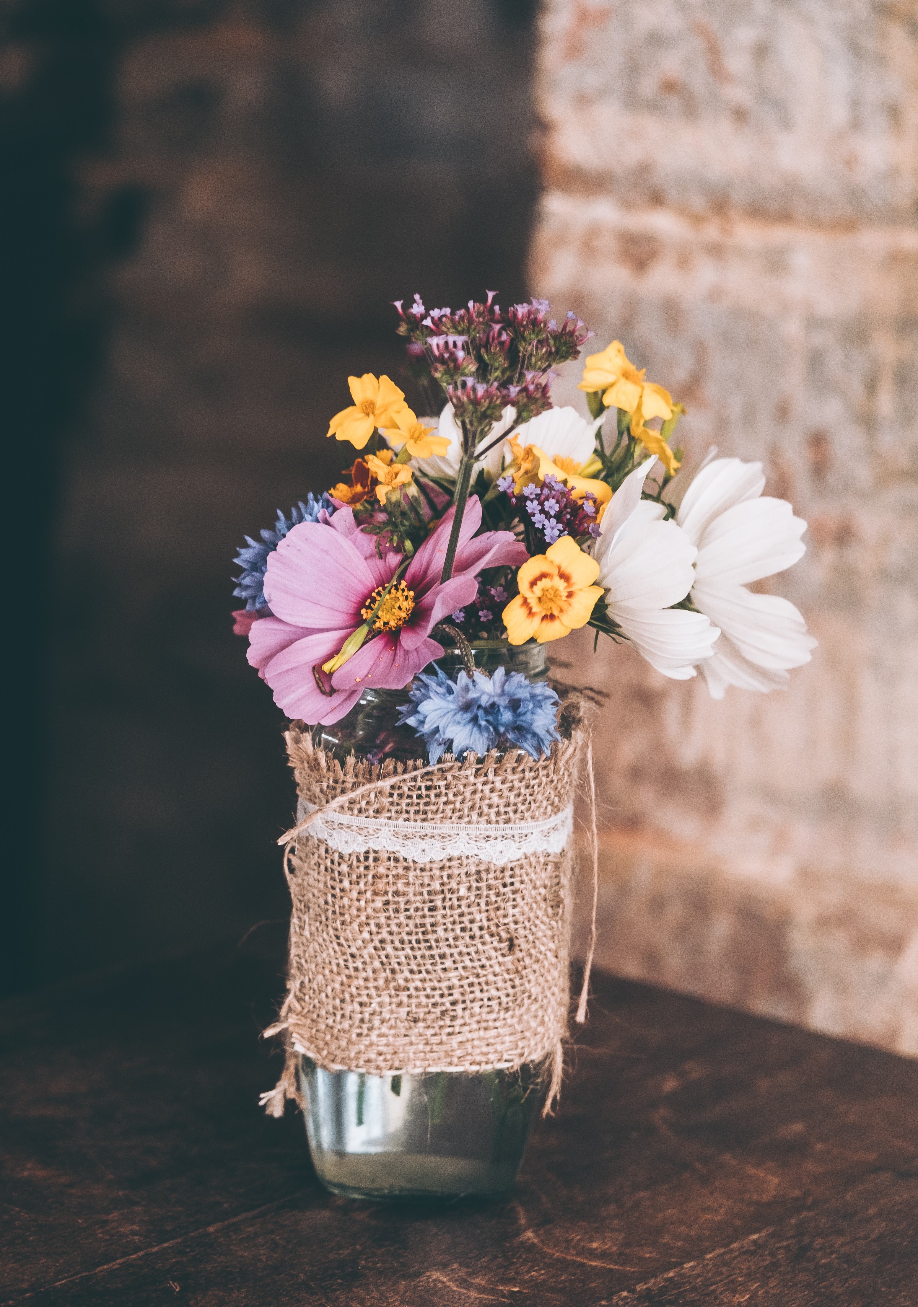 a bouquet of various flowers in a glass vase on a wooden surface, diverse flower vase 4k, Phone HD Wallpaper