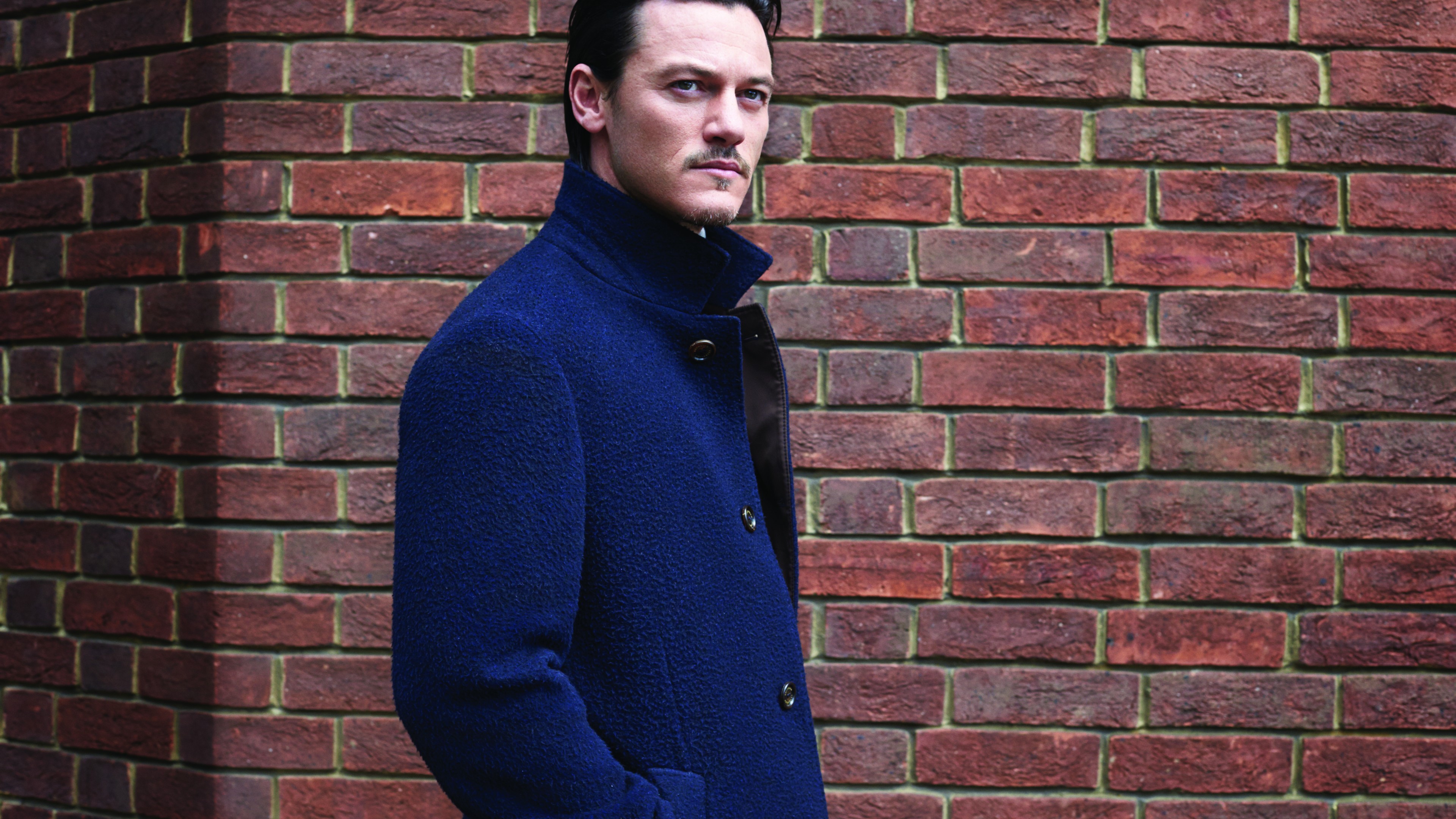 Luke Evans, Actor, blue cloak, brick wall, look, HD Wallpaper