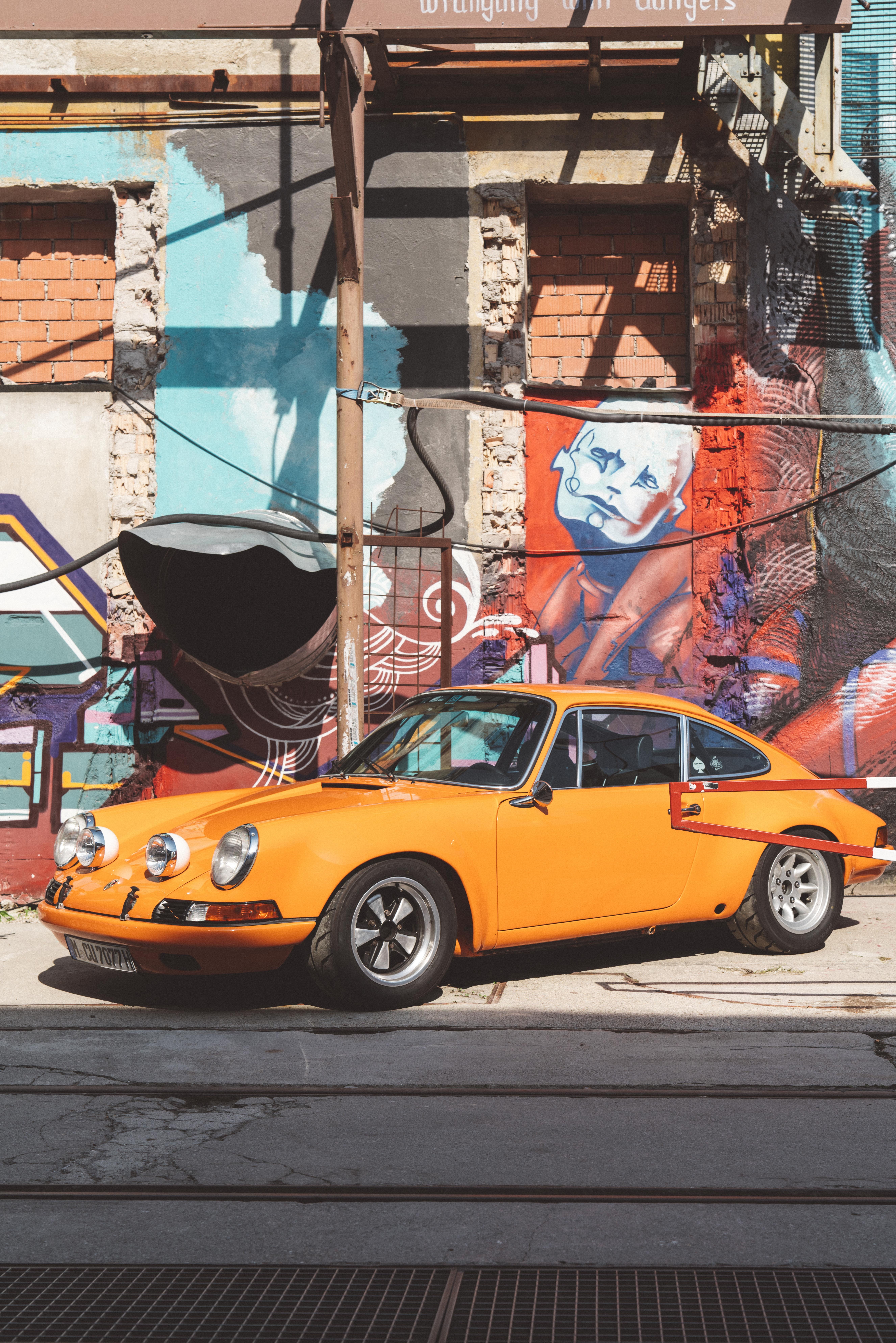 machine, porsche, city street, parked, spoke, 8K, taxi, billboard, outdoors, graffiti, street, built structure, transportation, sunlight, tire, nature, Phone HD Wallpaper