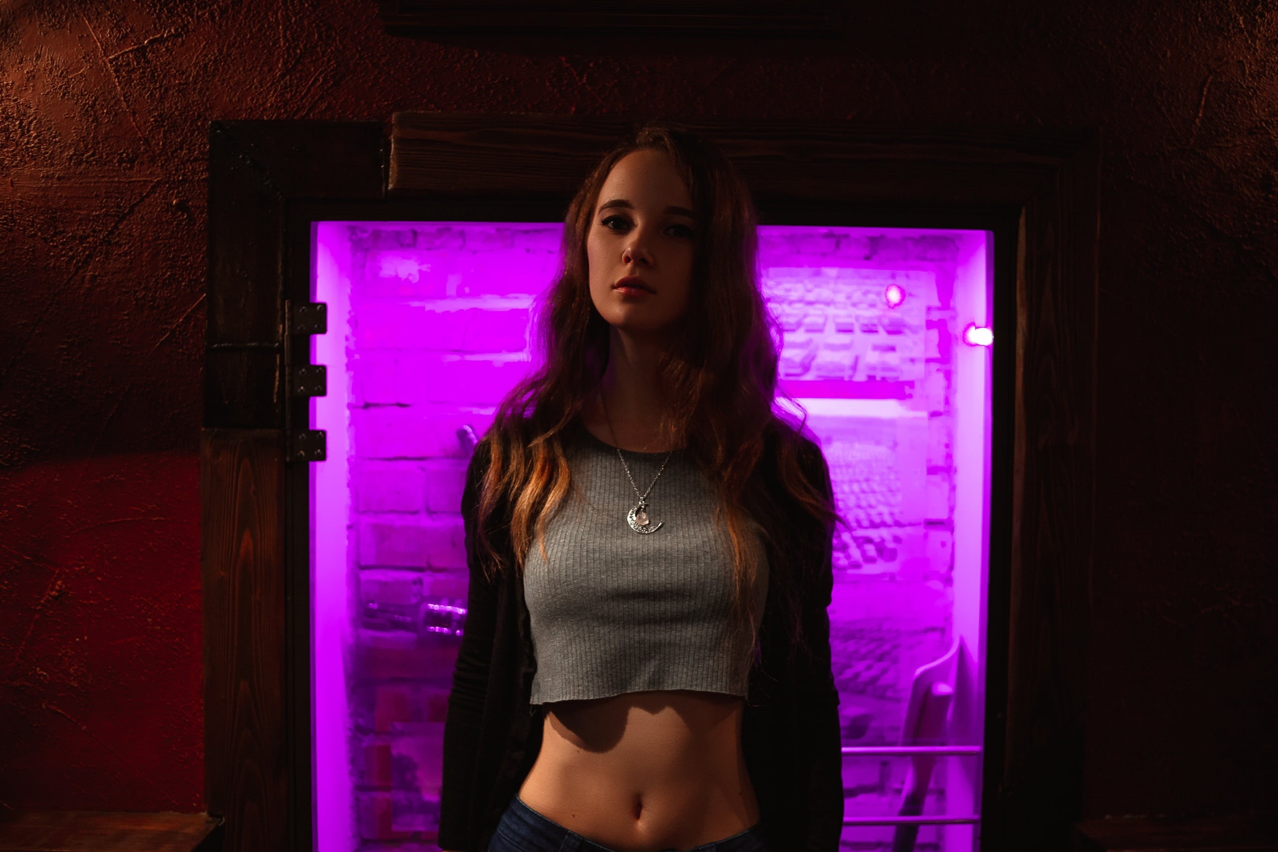 2K, grey tops, jeans, pink, crop top, neon lights, long hair, necklace, belly, model, dark, Ksana Stankevich, portrait, brunette, women, indoors, women, HD Wallpaper