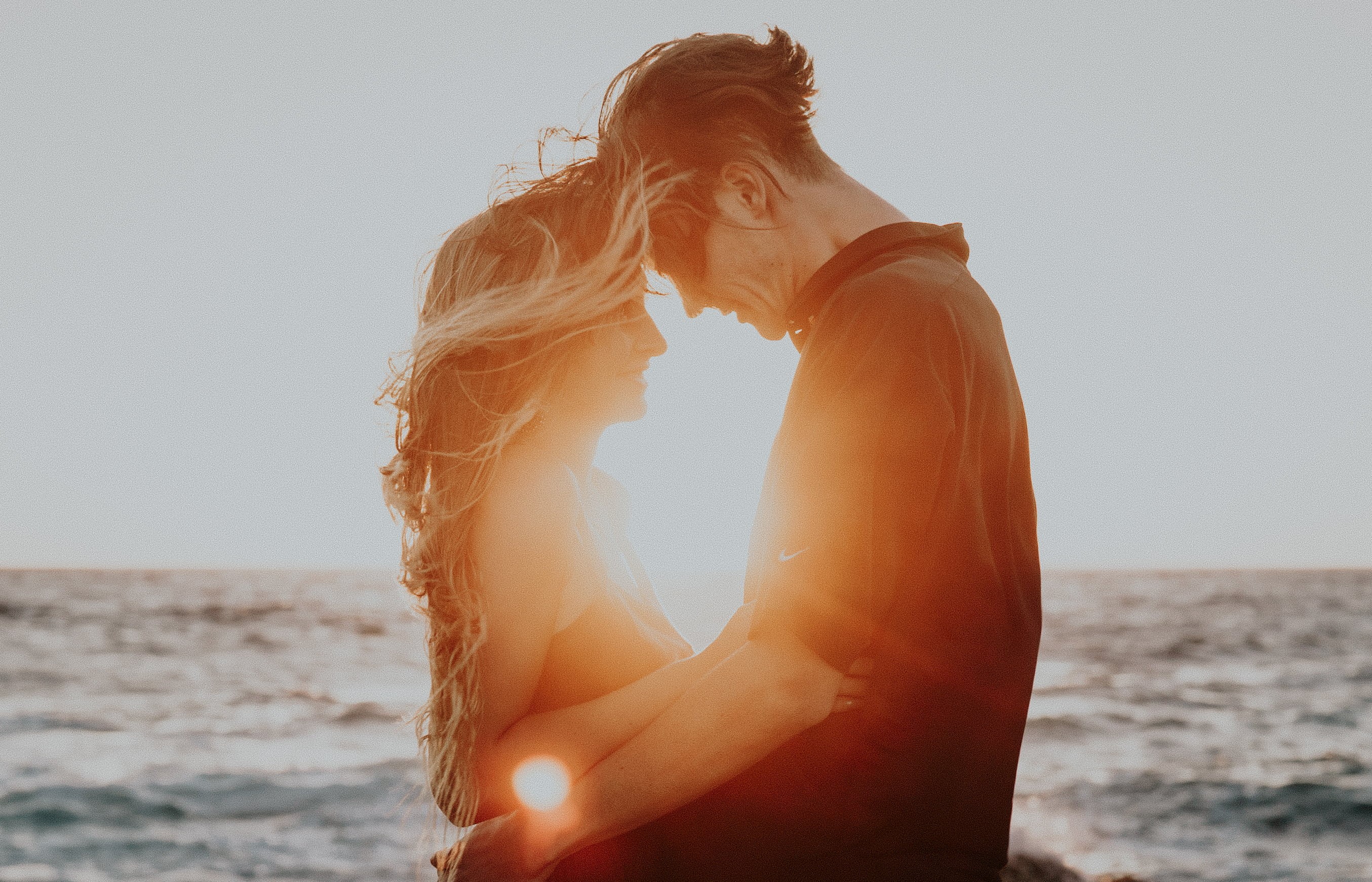 couple - relationship, beach, sunlight, hairstyle, sea, sunrise, summer, sun, hug, men, land, horizon over water, waves, horizon, outdoors, people, sunshine, HD Wallpaper