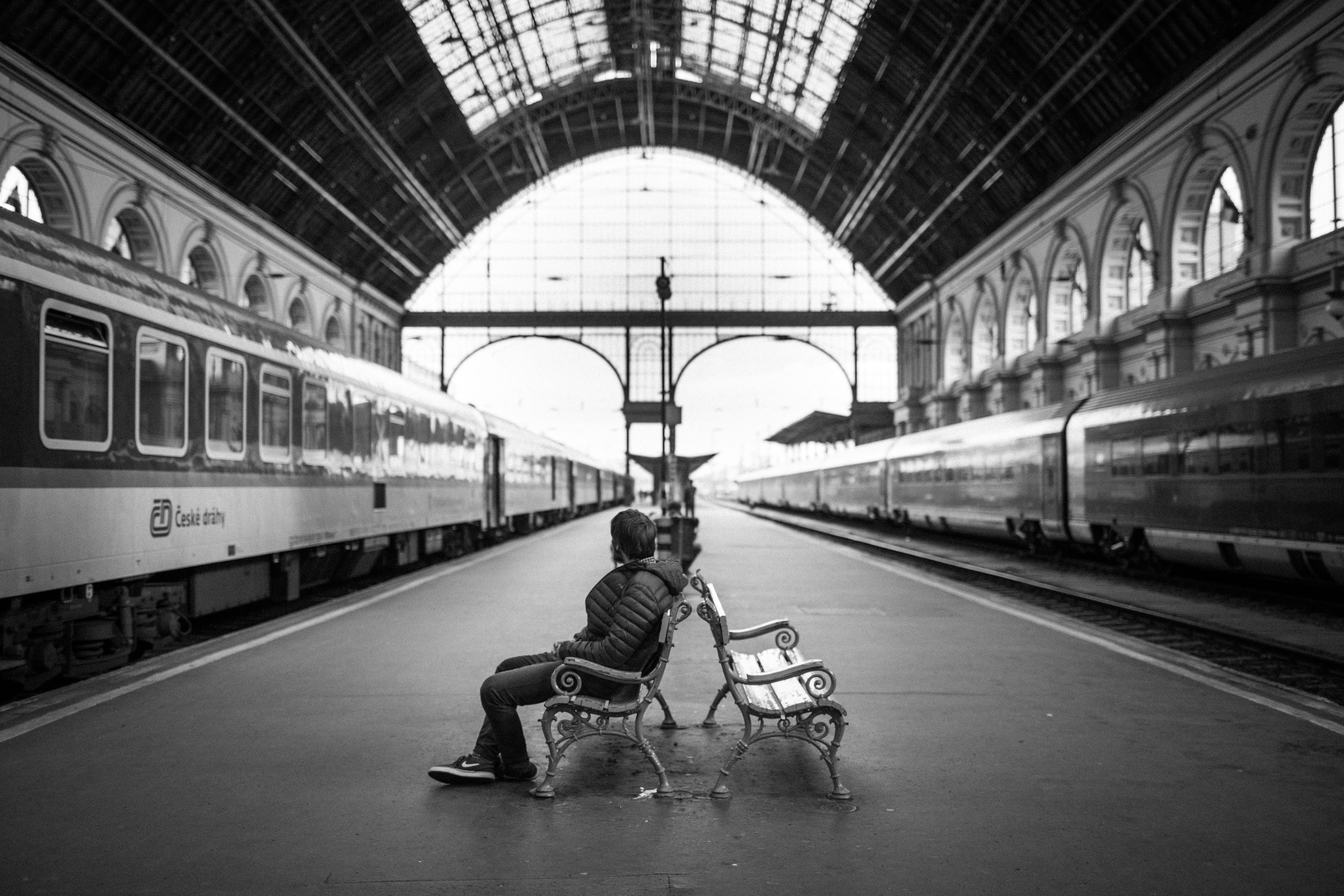 man, train station, grayscale, real people, railroad station platform, railroad station, railroad track, rail transportation, bench, mode of transportation, HD Wallpaper