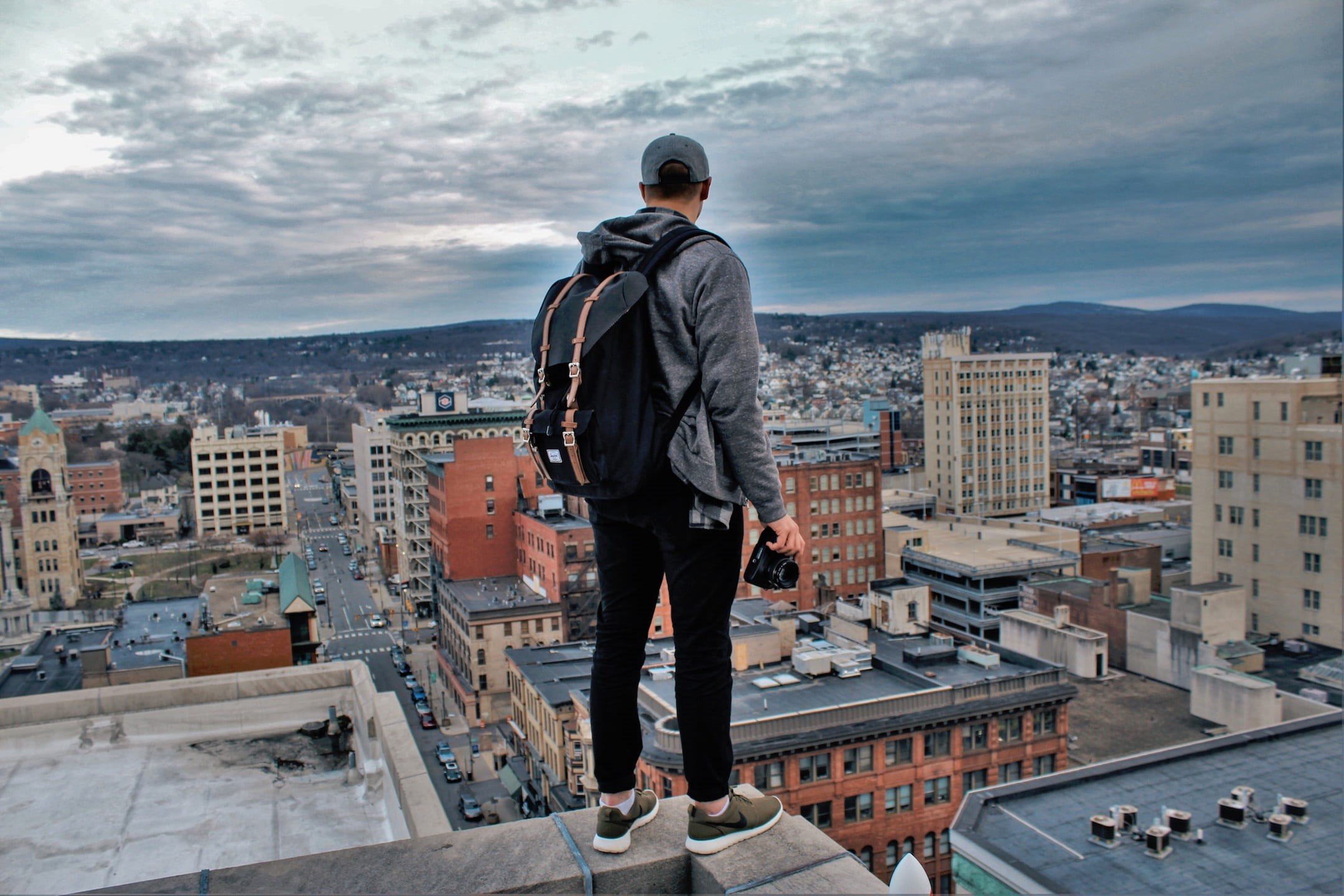 cloudy, real people, camera, millennials, backpack, building, city, rooftop, building exterior, cityscape, sky, man, black, lifestyles, rear view, guy, HD Wallpaper
