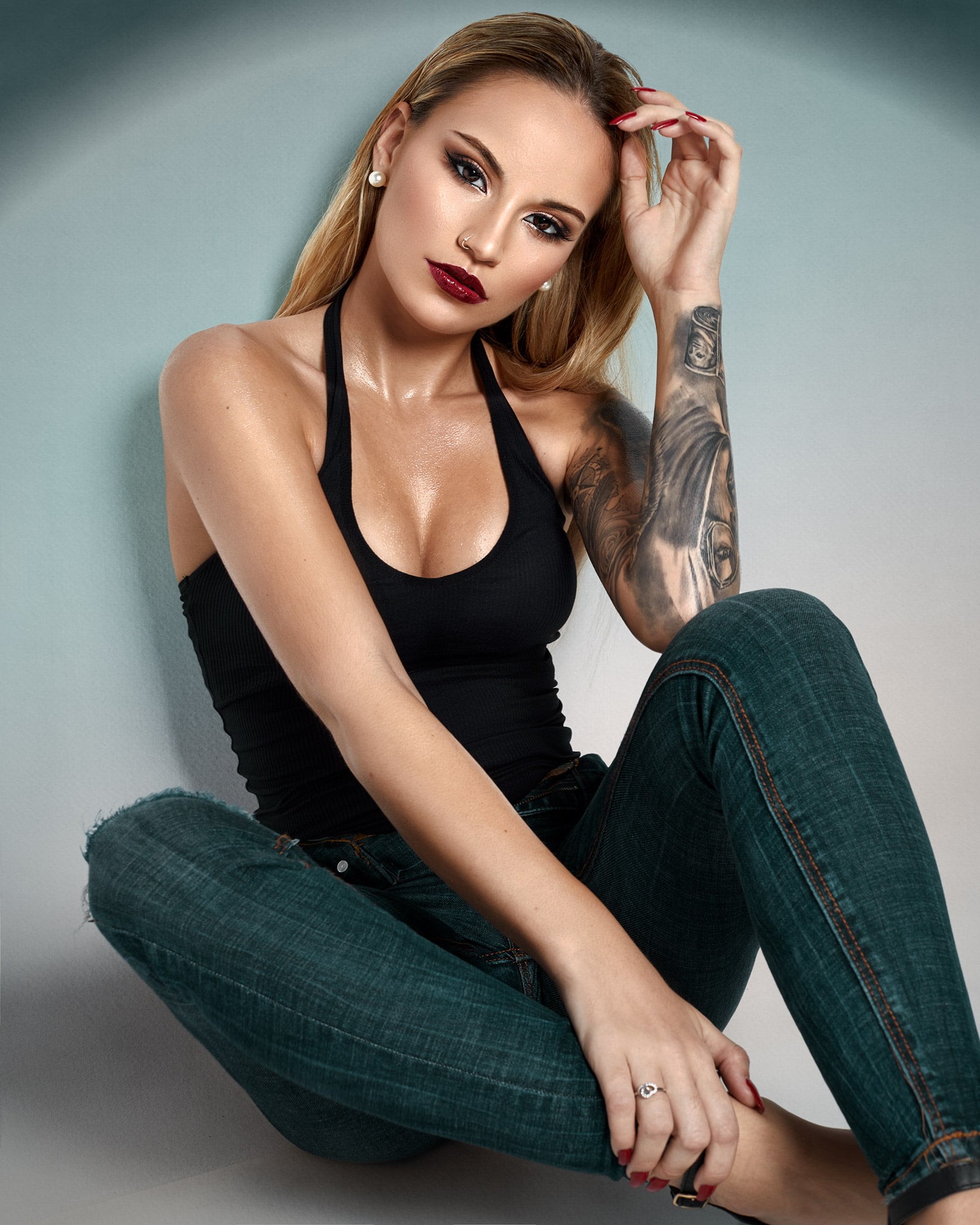 tattoo, looking at viewer, 1080P, pierced nose, sweat, eyeshadow, jeans, wall, women, cleavage, denim, tank top, beads, body oil, red nails, straight hair, Phone HD Wallpaper