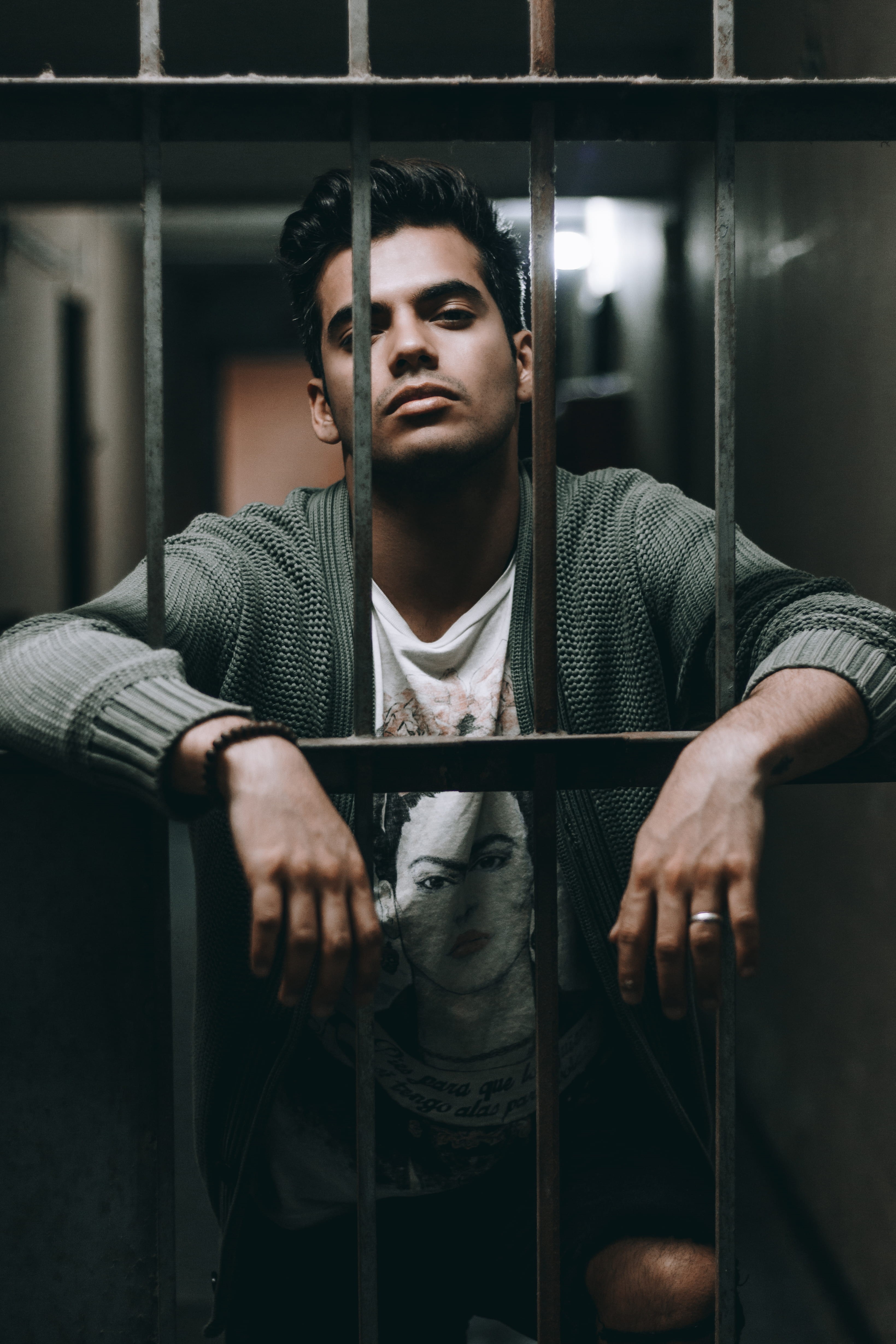 holding, prison, looking at camera, front view, casual clothing, young men, one person, behind, leisure activity, 4K, metal, sitting, jail, young adult, Phone HD Wallpaper
