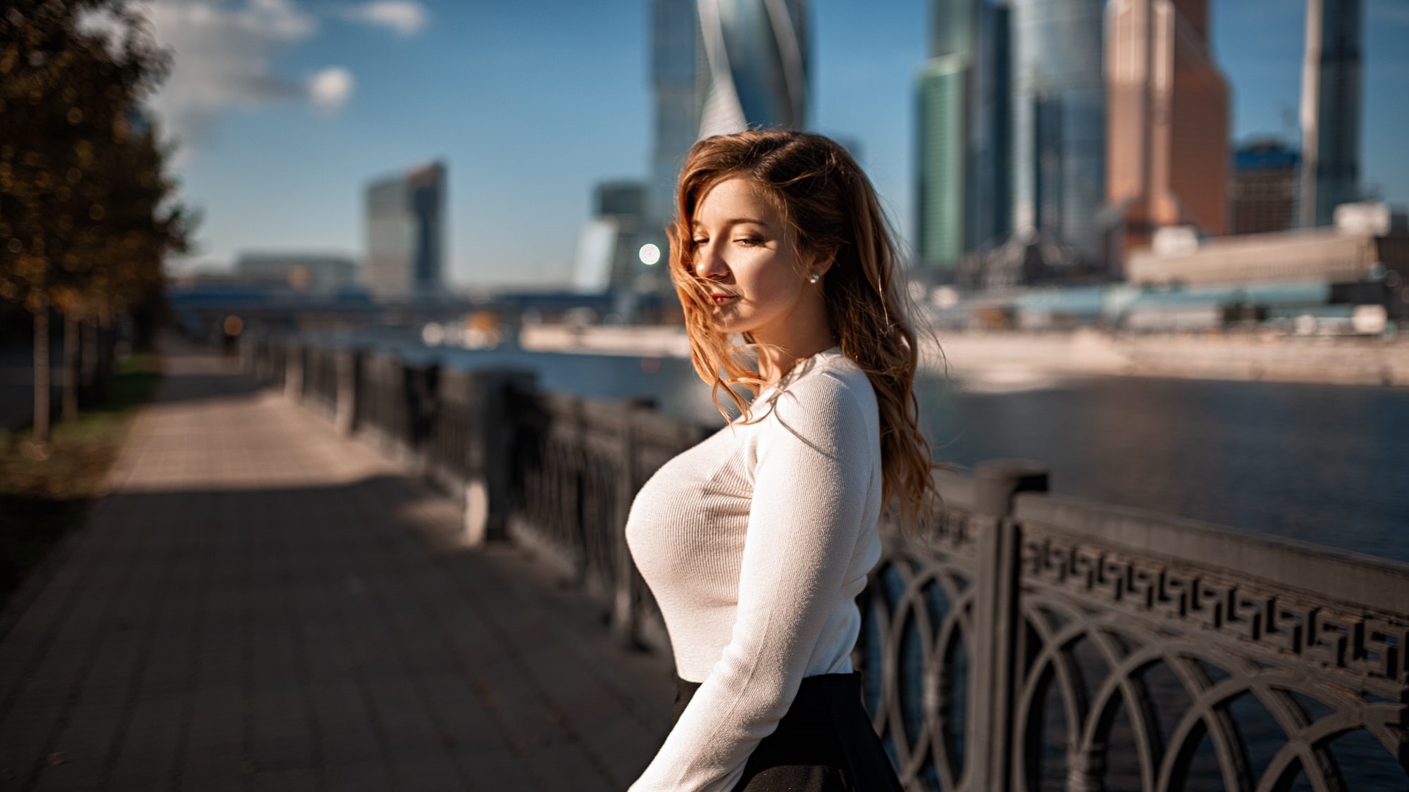 pearl earrings, building, model, sweater, sidewalks, black skirts, Grigoriy Lifin, portrait, depth of field, brunette, white sweater, smiling, trees, hair in face, HD Wallpaper
