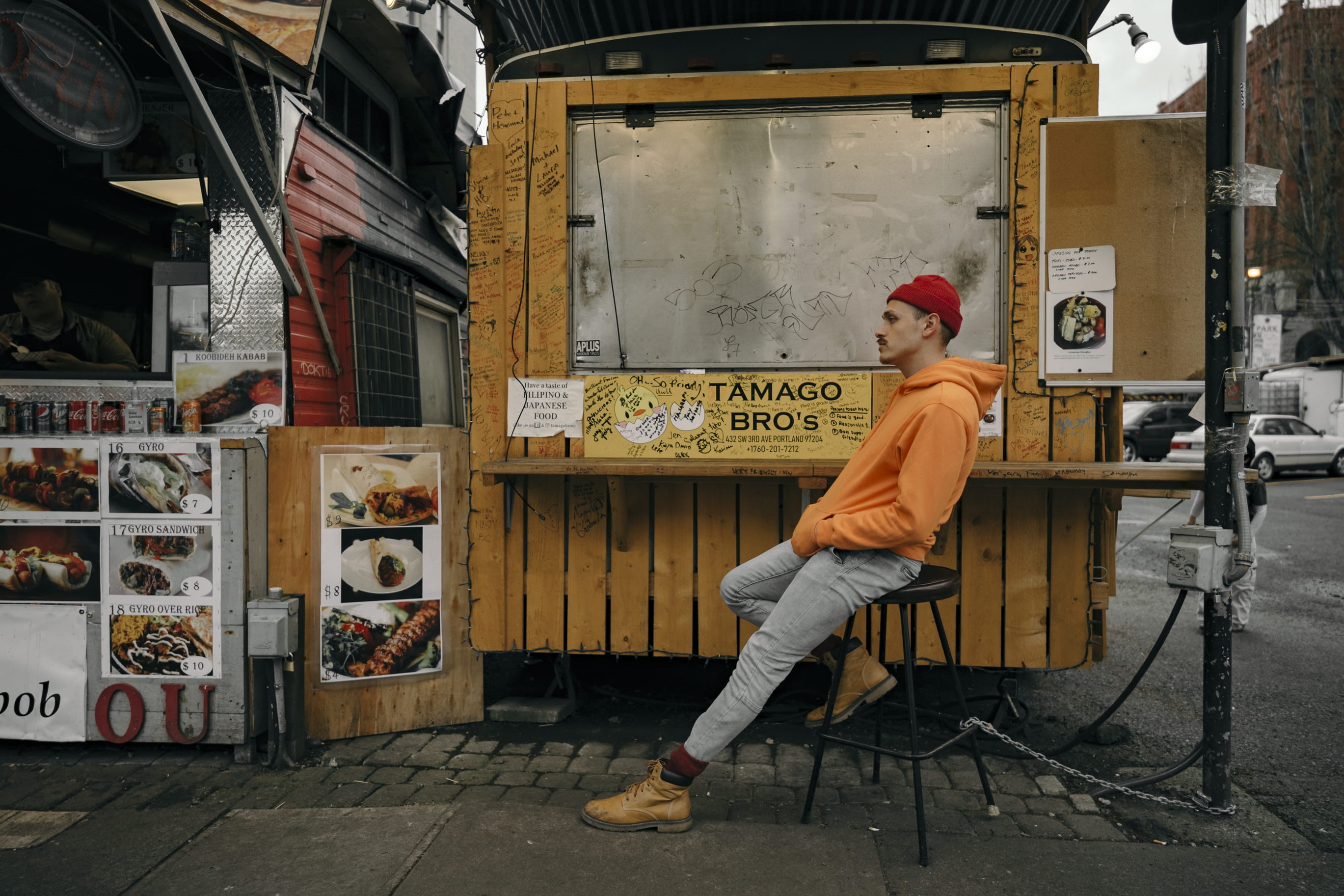 sell, red hat, art and craft, food, store, pavement, menu, graffiti, sitting, daylight, man, street, leisure activity, lifestyles, road, hoodie, one person, HD Wallpaper