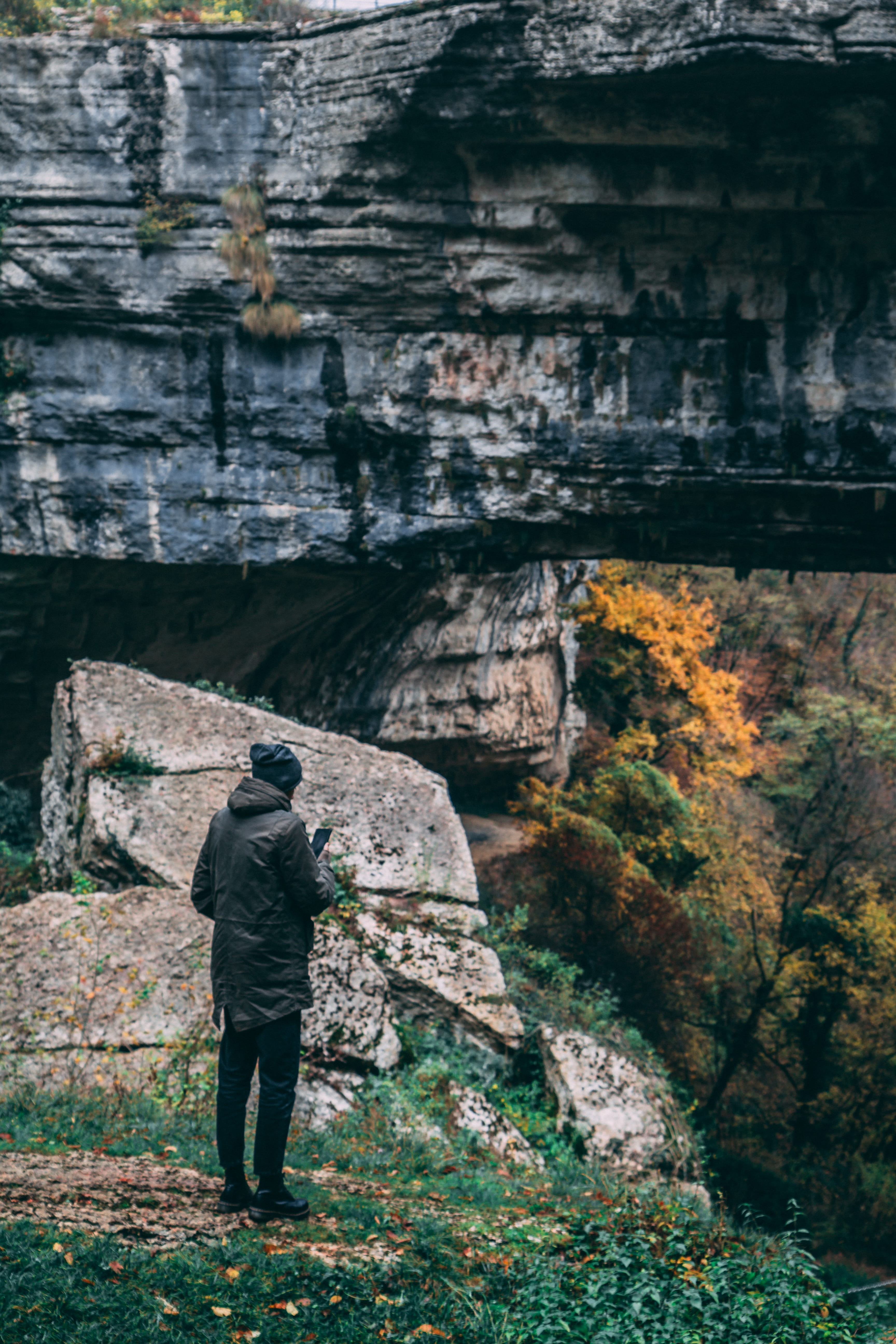 rear view, daylight, outdoors, traveller, standing, explorer, boulders, nature, real people, mountain, rock formation, full length, outfit, plant, trip, Phone HD Wallpaper