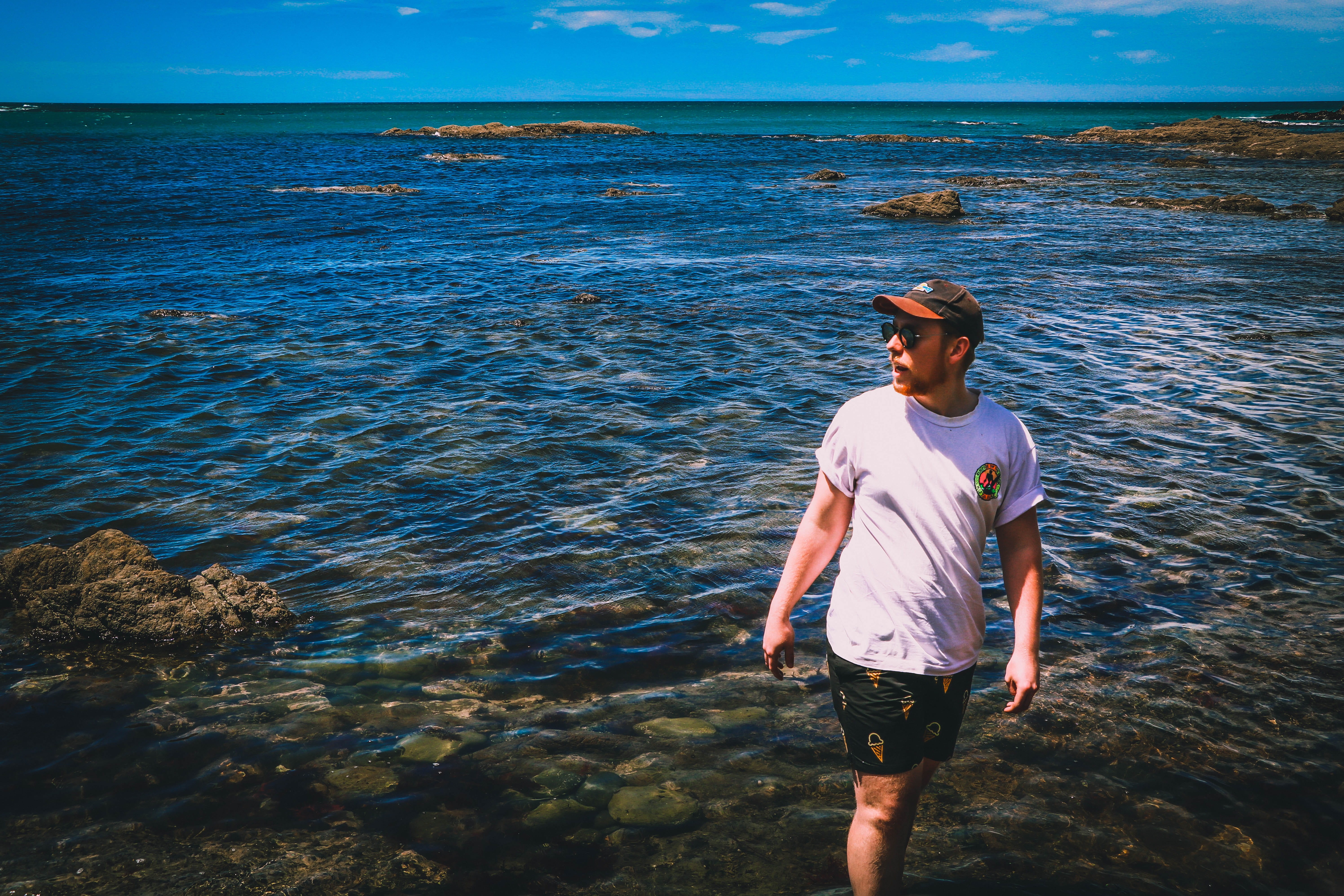 rocks, shorts, lifestyles, one person, water, young adult, nature, outdoors, three quarter length, solid, sea, beauty in nature, scenics - nature, new zealand, HD Wallpaper