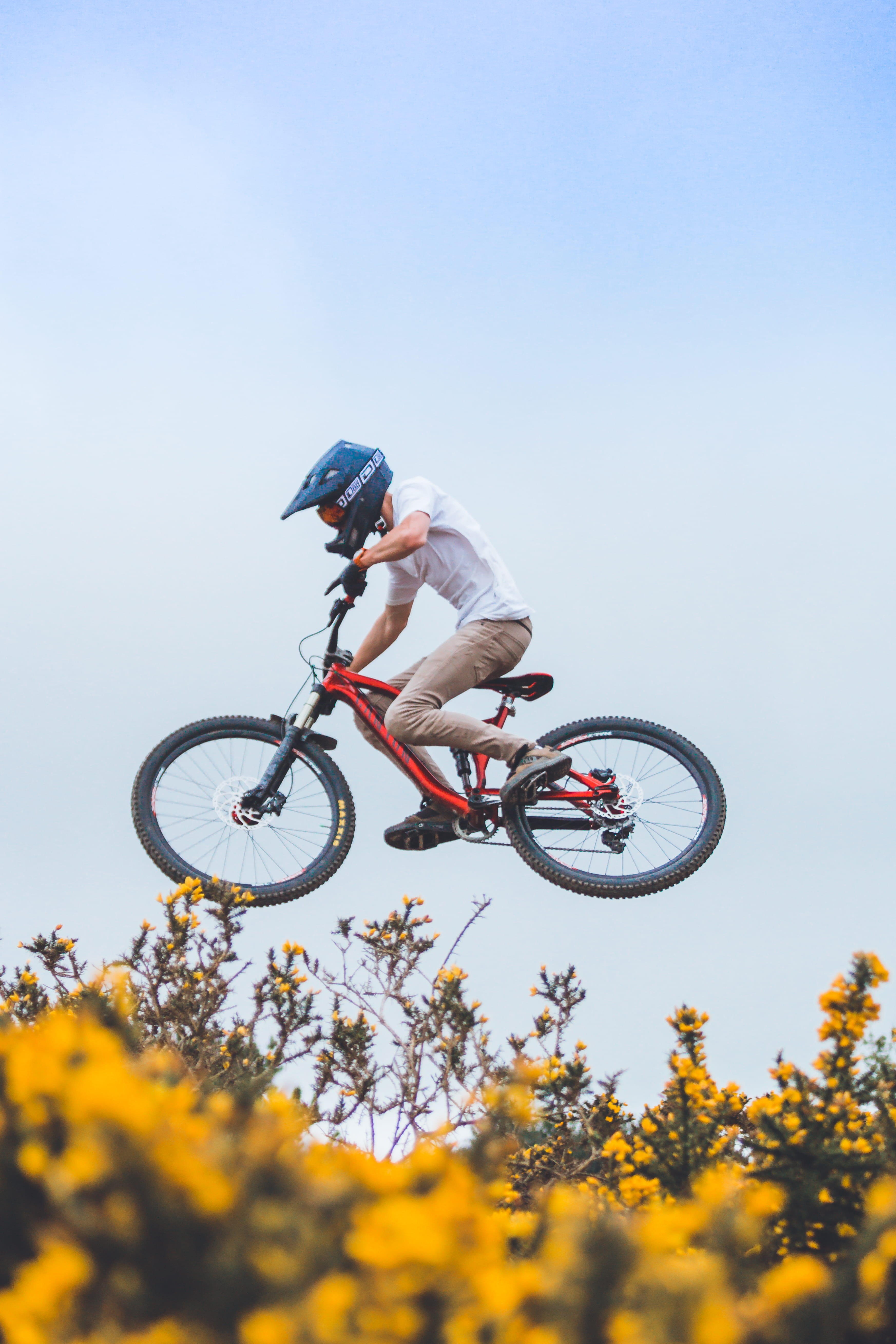 full length, helmet, mountain, biker, leisure activity, outdoors, nature, clear sky, mid-air, flower, 5K, bicycle, bush, person, transportation, real people, Phone HD Wallpaper