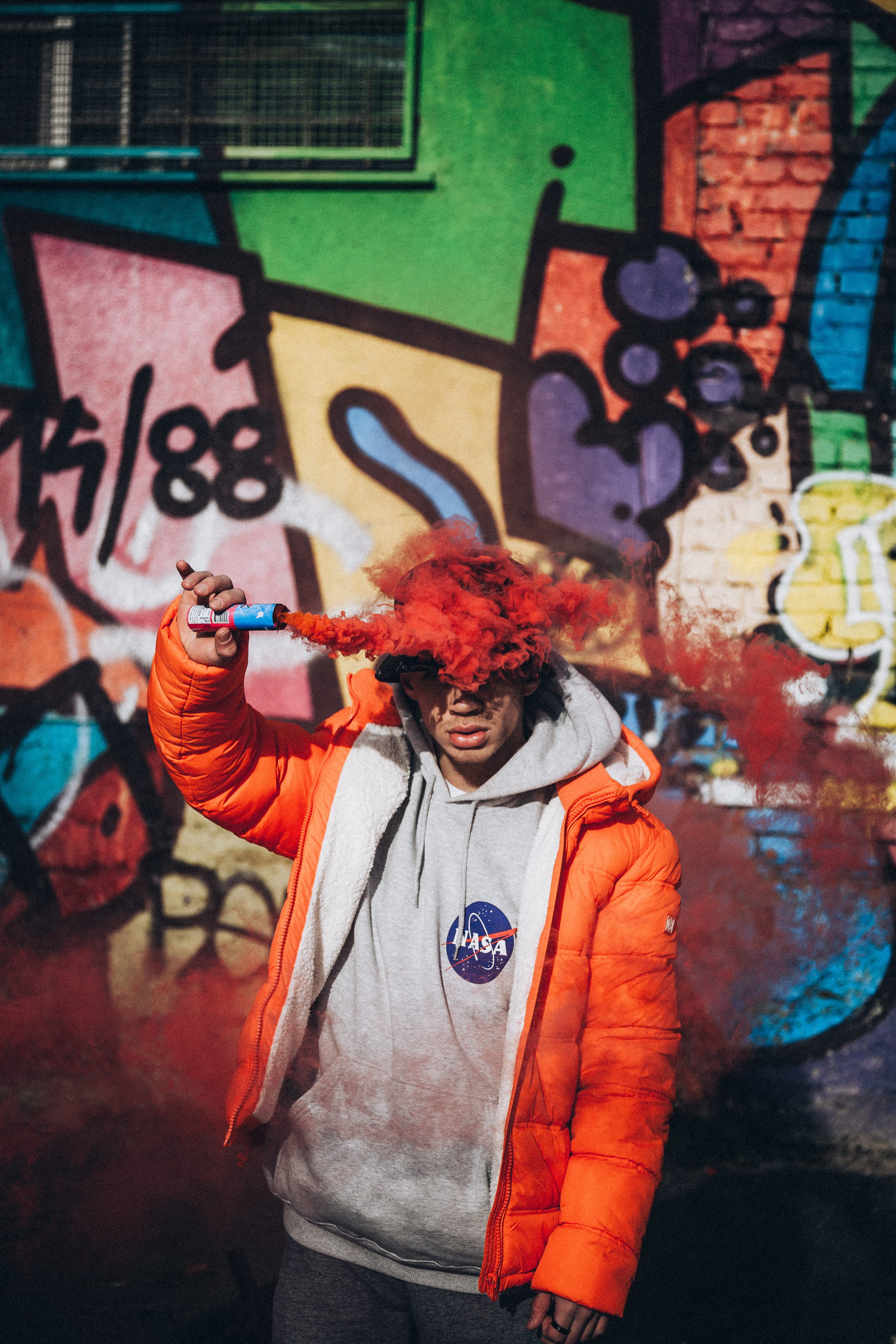 wall, clothing, architecture, jacket, abstract, casual clothing, graffiti, human, holding, hat, hair, smoke, urban, brick, red, multi colored, waist up, Phone HD Wallpaper
