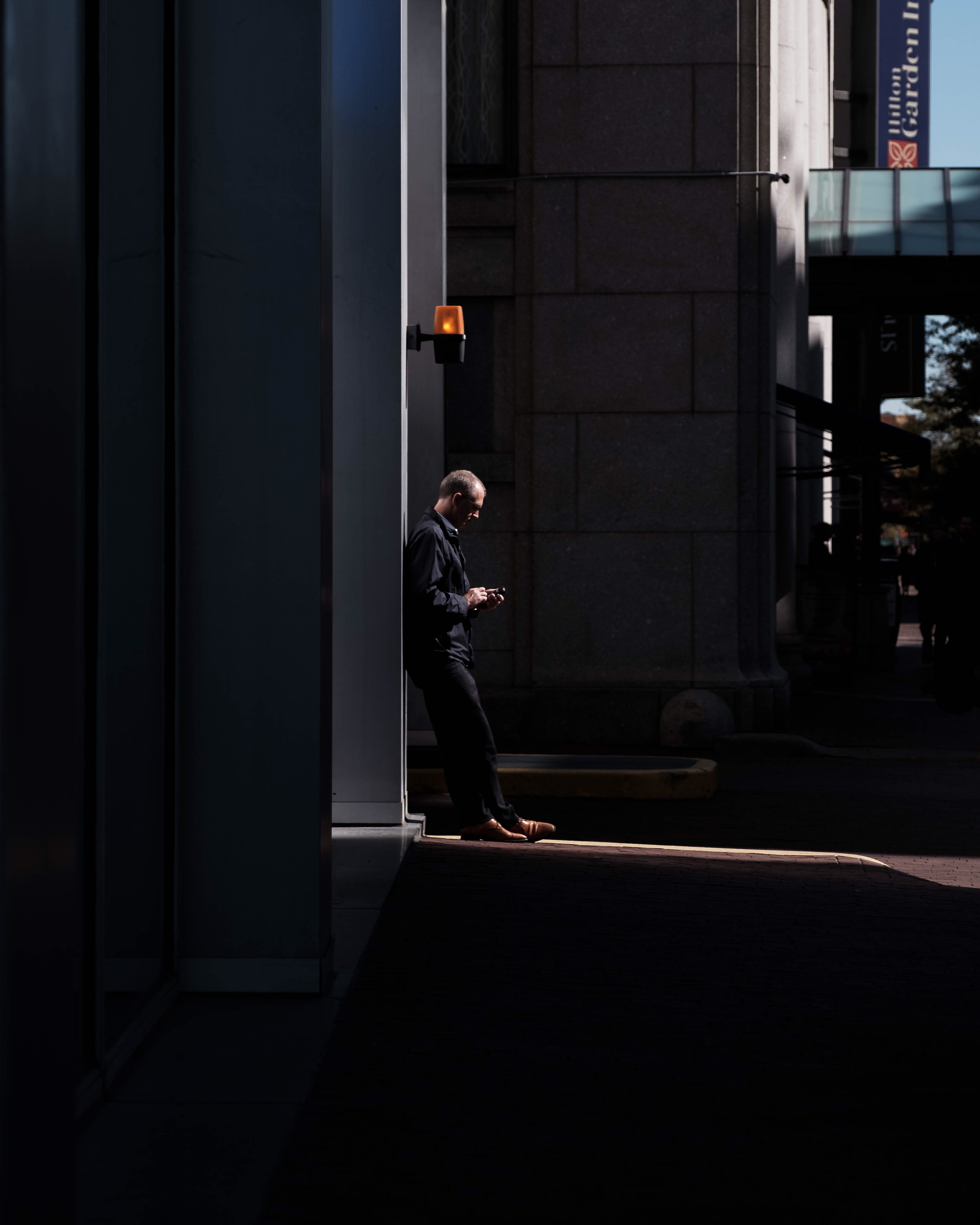 standing, entrance, man, walking, urban, men, outdoors, lifestyles, building, dark, built structure, wall lamp, town, 4K, near, light, clothing, building exterior, Phone HD Wallpaper