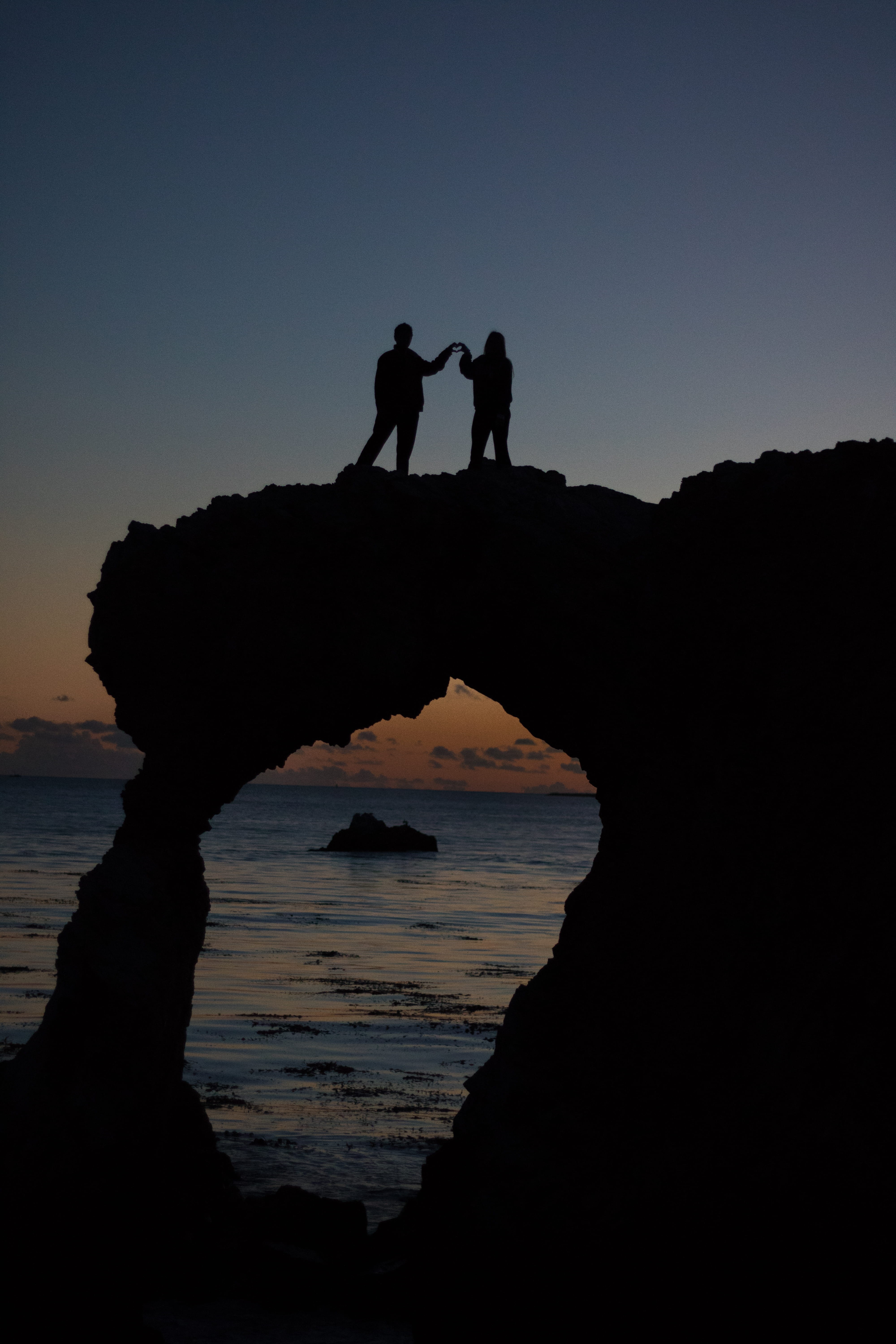 person, rock - object, couple - relationship, beach, sea, standing, leisure activity, people, men, couple, two, sky, persons, atop, arch, silhouette, land, Phone HD Wallpaper