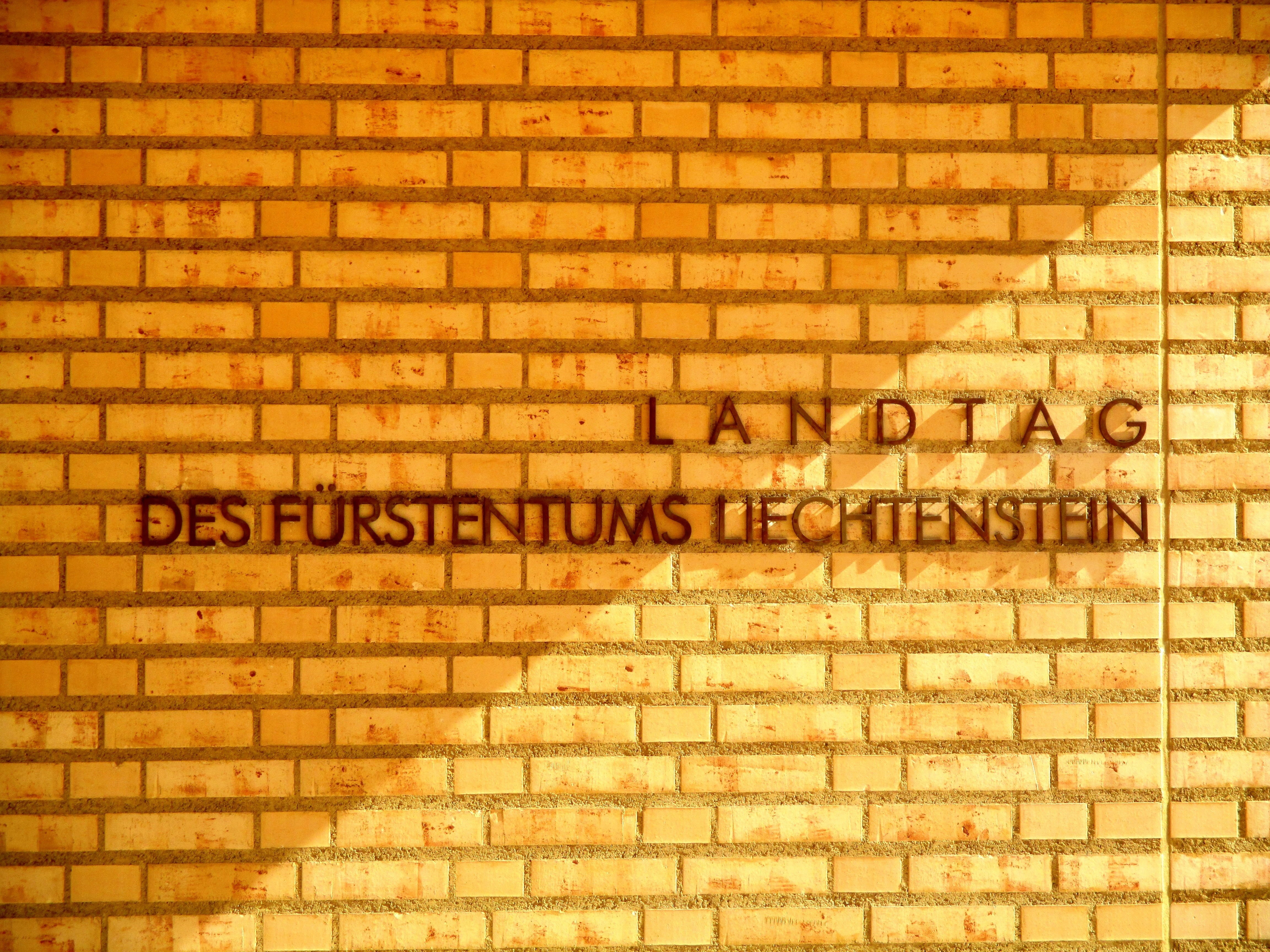 western script, brick light, brick, vaduz, sign, text, sunlight, wall - building feature, landtag of principality of liechtenstein, writing, message, outdoors, HD Wallpaper