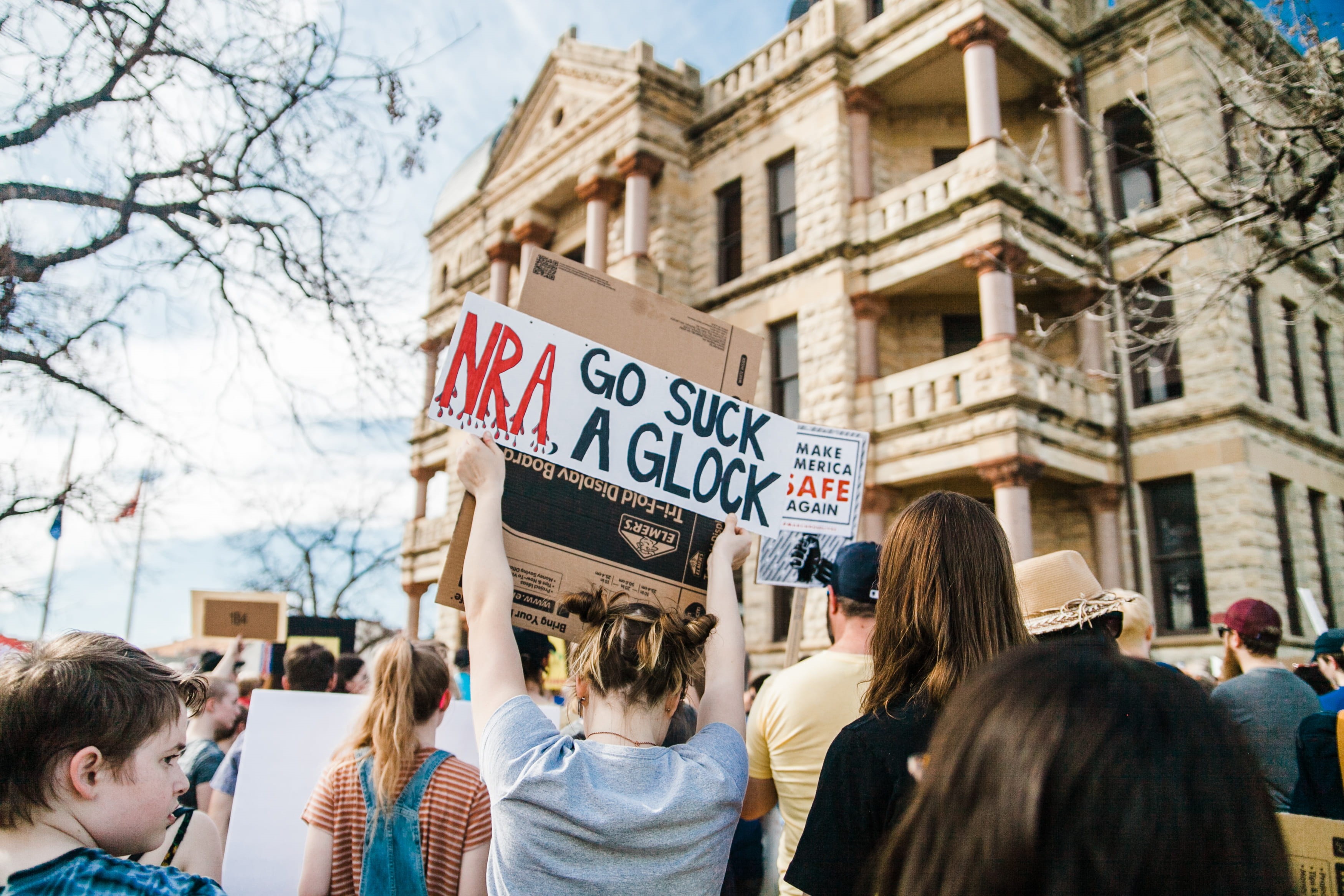 real people, day, message, building, text, holding, adult, showing, city, gun, front, together, street, rally, people, assembly, activist, built structure, HD Wallpaper