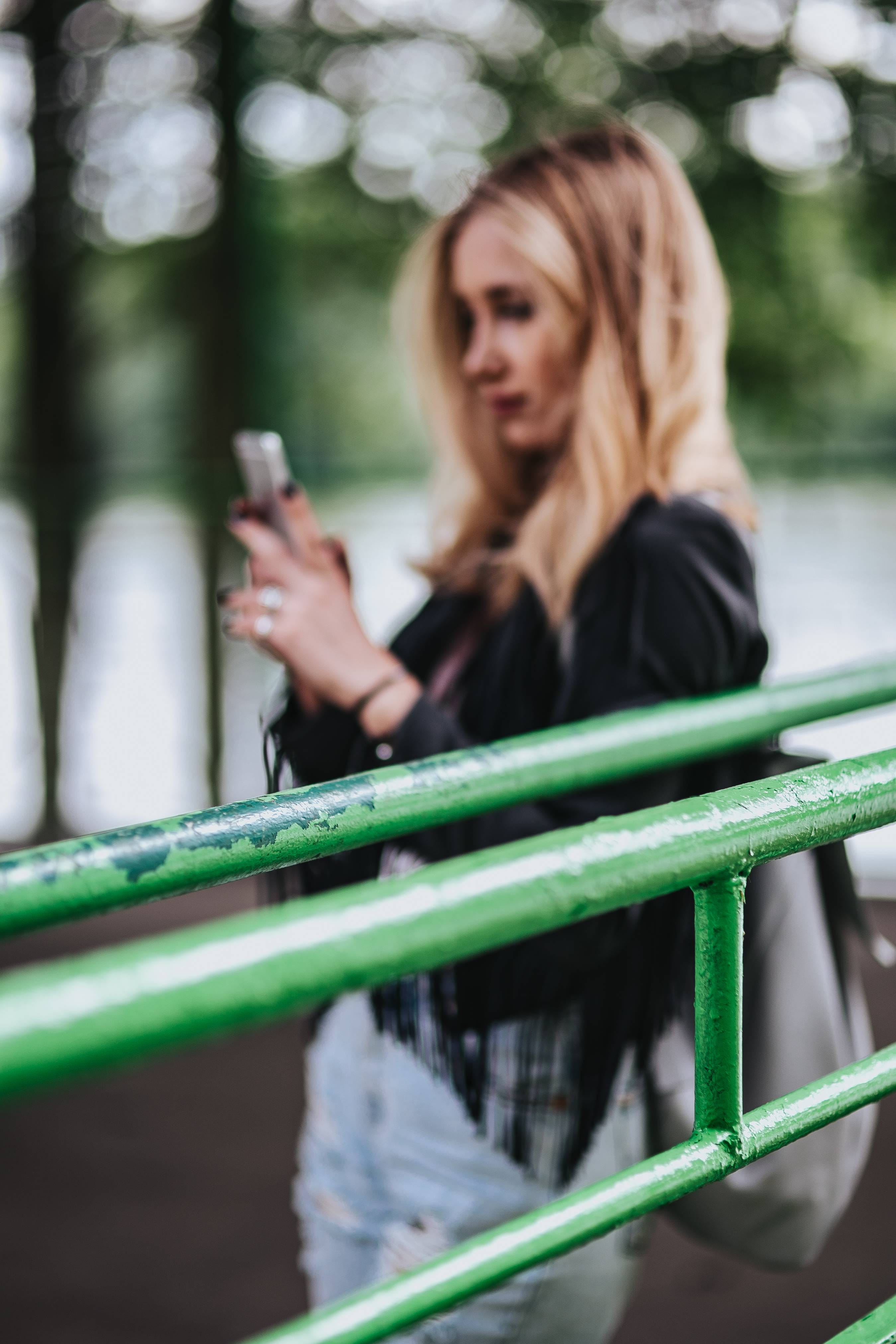 focus on foreground, Blonde, female, adult, girl, woman, park - Man Made Space, smiling, jeans, pretty, beautiful, rail, holding, portrait, hair, females, Phone HD Wallpaper