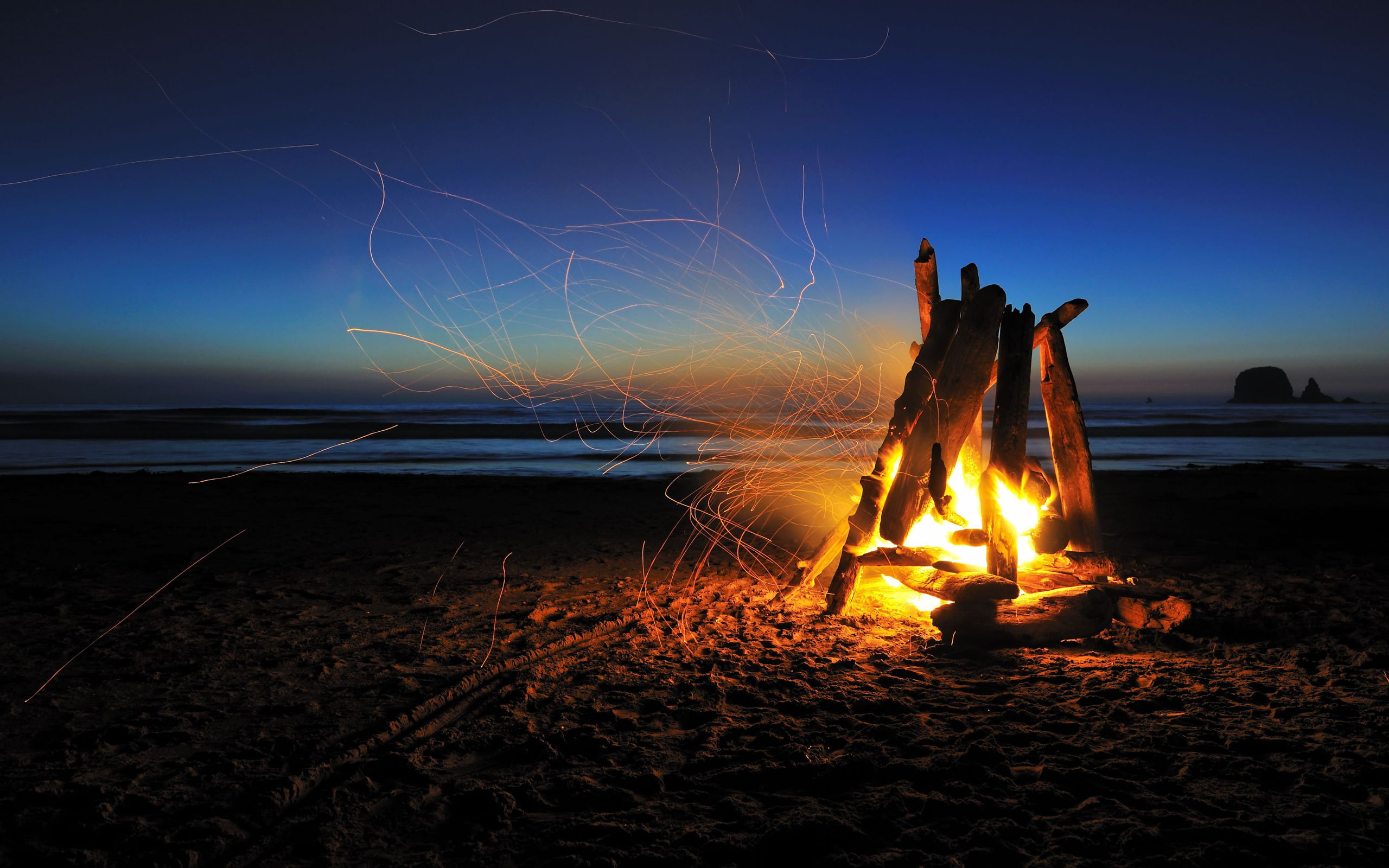 sparks, light, fire - Natural Phenomenon, back Lit, the ocean, sand, the darkness, outdoors, sun, adult, vacations, twilight, firewood, men, no people, HD Wallpaper