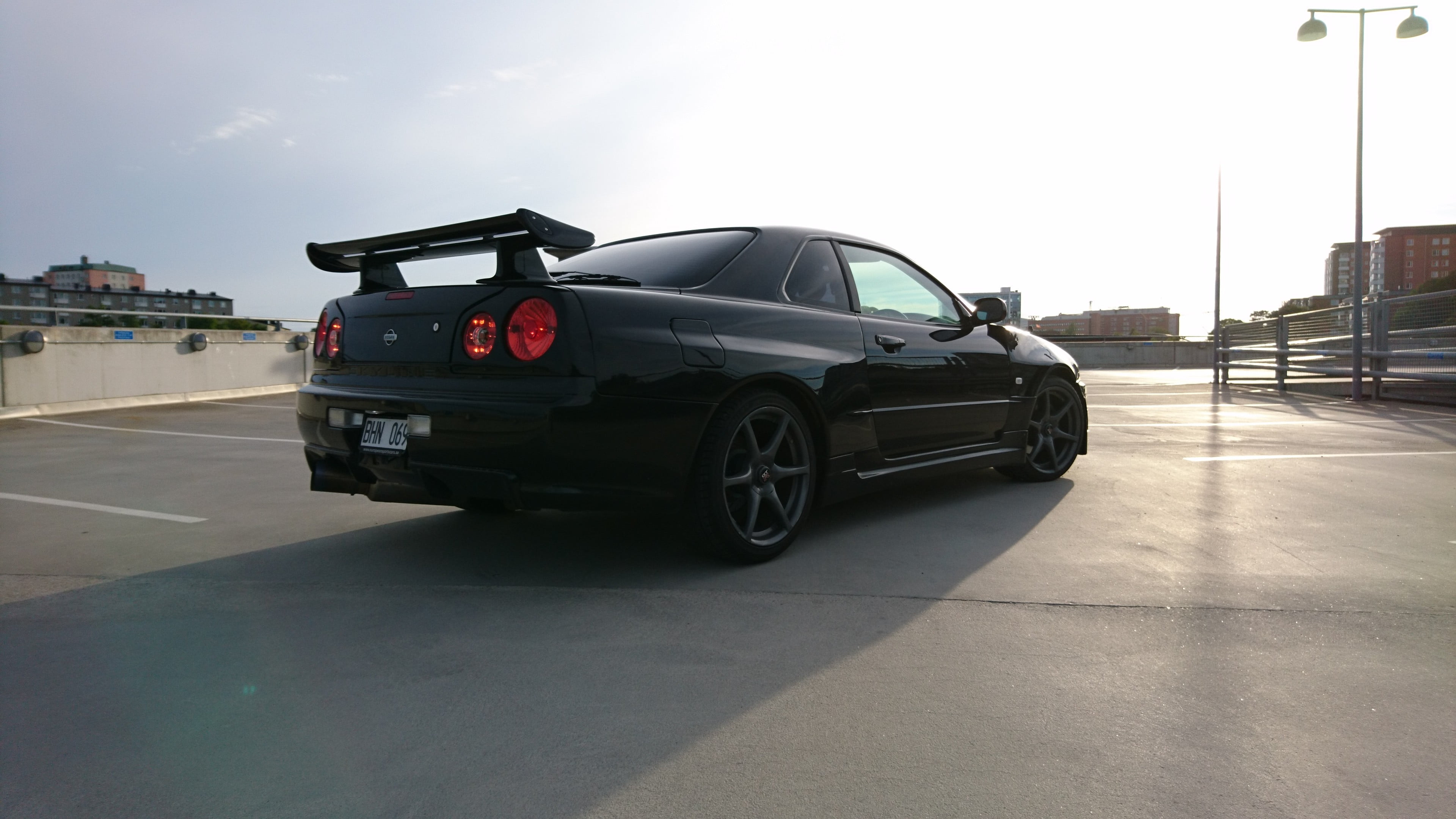 Nissan Skyline GT-R R34, architecture, travel, 4K, building exterior, skyline, parking lot, built structure, mercedes, sky, nature, Nissan, benz, street, HD Wallpaper