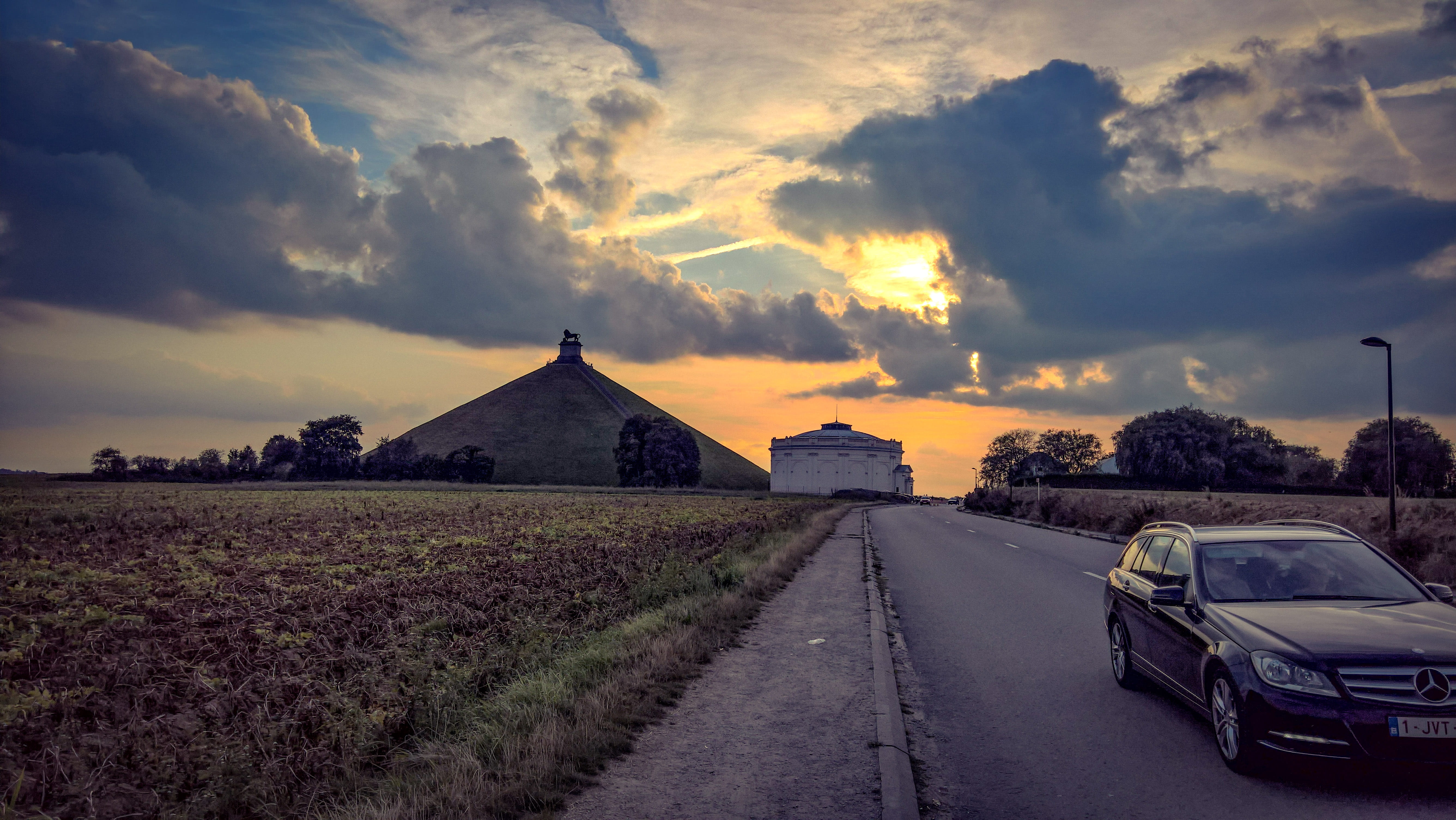 direction, mode of transportation, cloud - sky, sunset, land, belgium, sky, transportation, field, land vehicle, clouds, plant, car, grass, lion, 5K, waterloo, HD Wallpaper