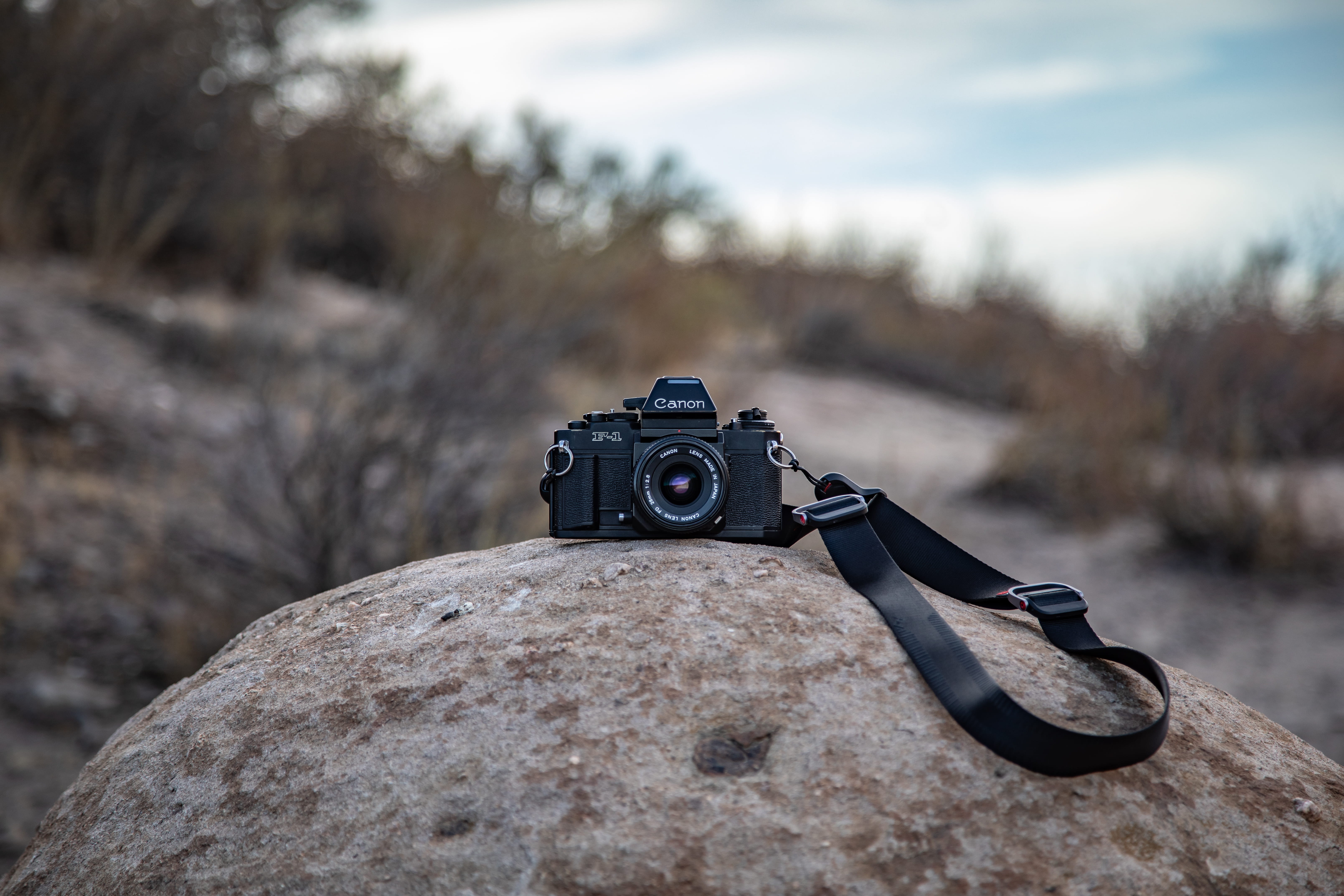 strap, land, 5K, camera gear, 35mm, canon, close-up, cloud - sky, retro, dslr, photography, outdoors, black, rock - object, electronics, analog, wilderness, HD Wallpaper
