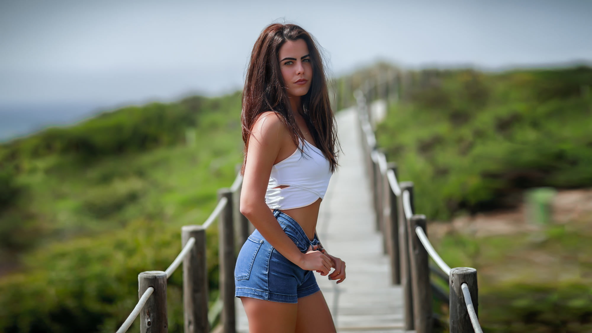 clothing, jean shorts, tanned, adult, Pedro Courelas, casual clothing, one person, women outdoors, bokeh, outdoors, hairstyle, railing, shorts, looking at camera, HD Wallpaper