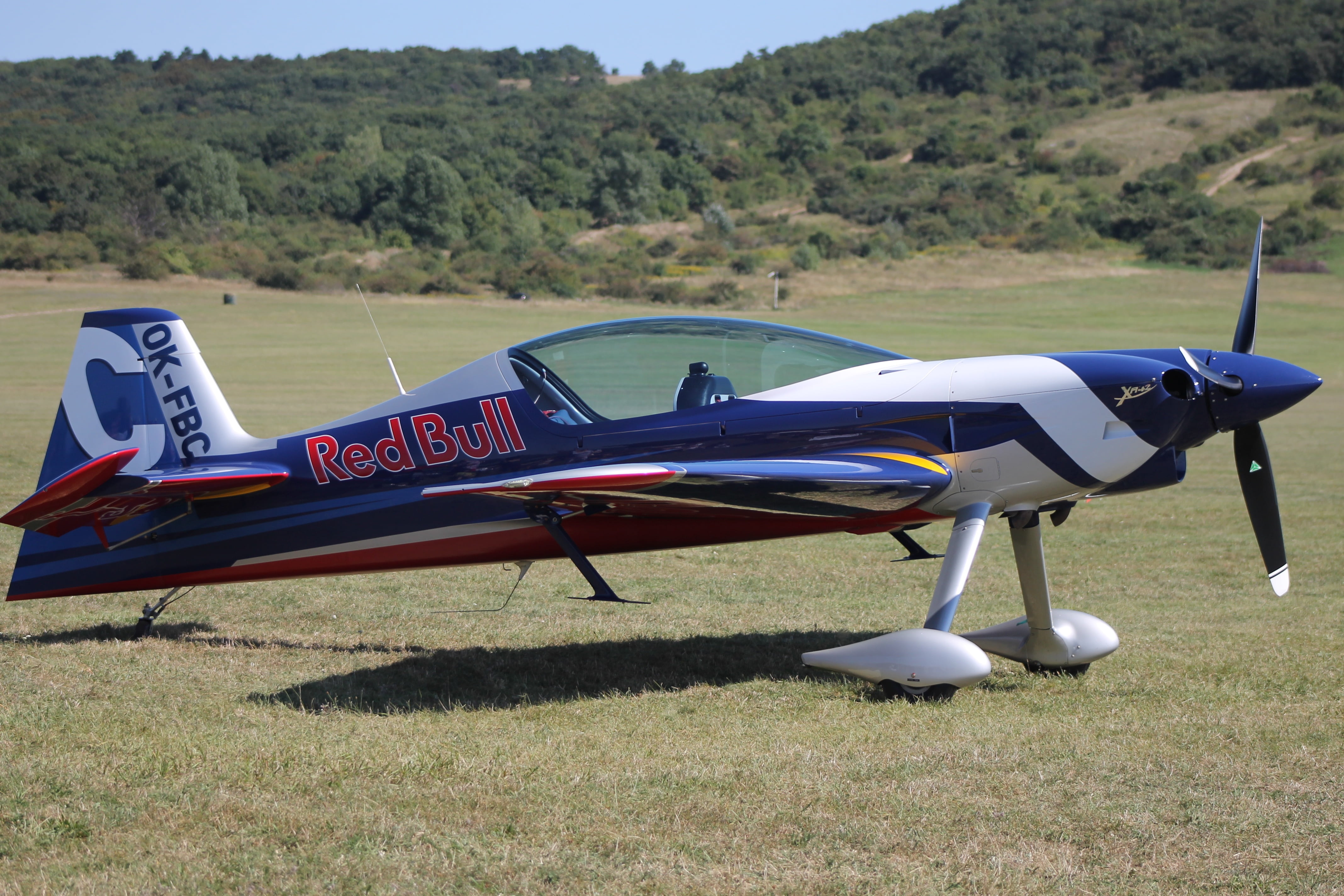 hangar 7, engine, transportation, fly, field, propeller, no people, airplane, side view, nature, day, red bull, grass, sunlight, aircraft Wing, flight, HD Wallpaper