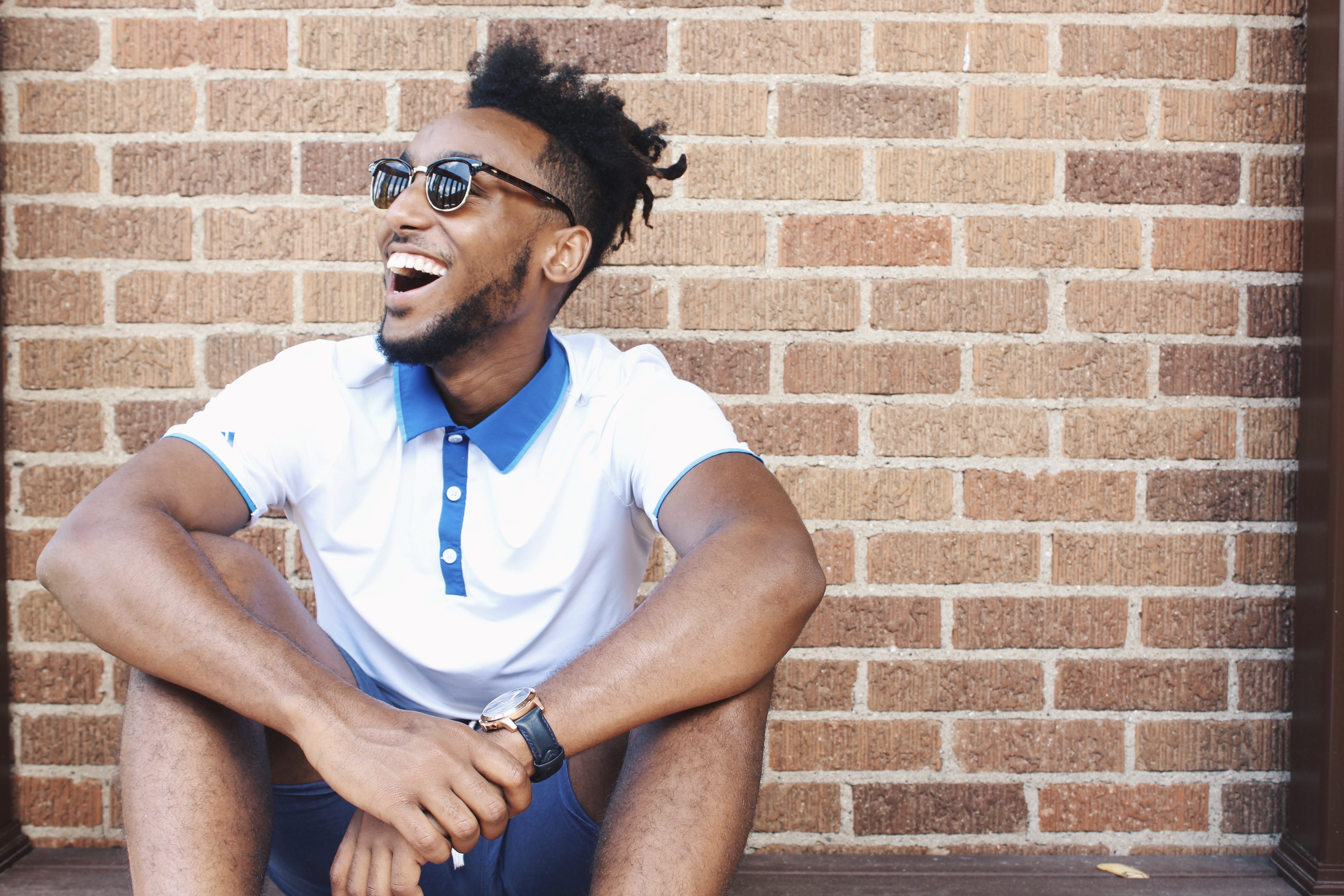 brick wall, wearing, real people, shirt, lifestyles, shorts, young men, smiling, hairstyle, wall, looking away, sitting, leisure activity, polo, man, fashion, HD Wallpaper