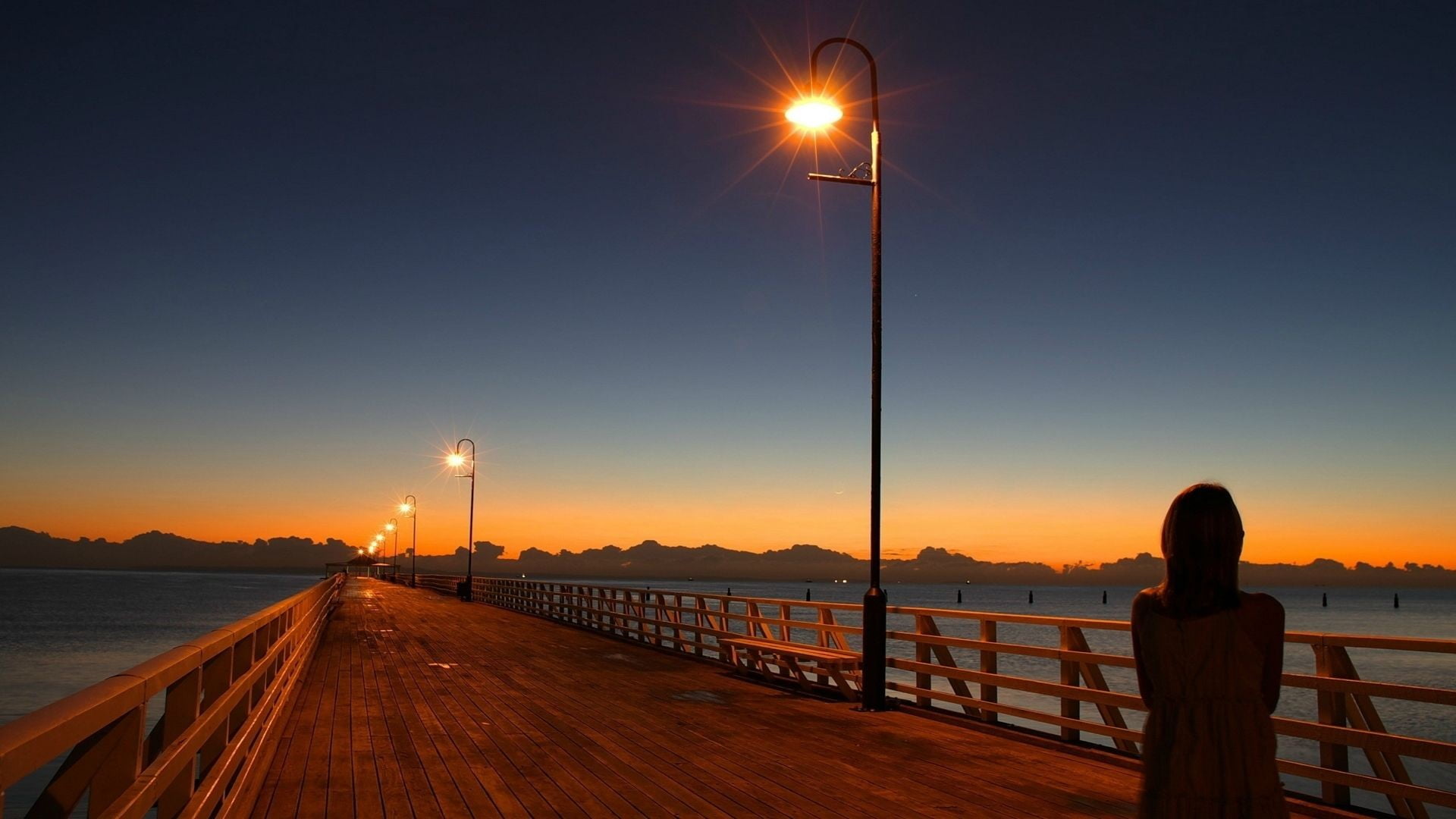 outdoors, railing, street, metal, post, sunset, lighting equipment, 1080P, sea, orange color, street light, water, one person, gray, pier, illuminated, HD Wallpaper