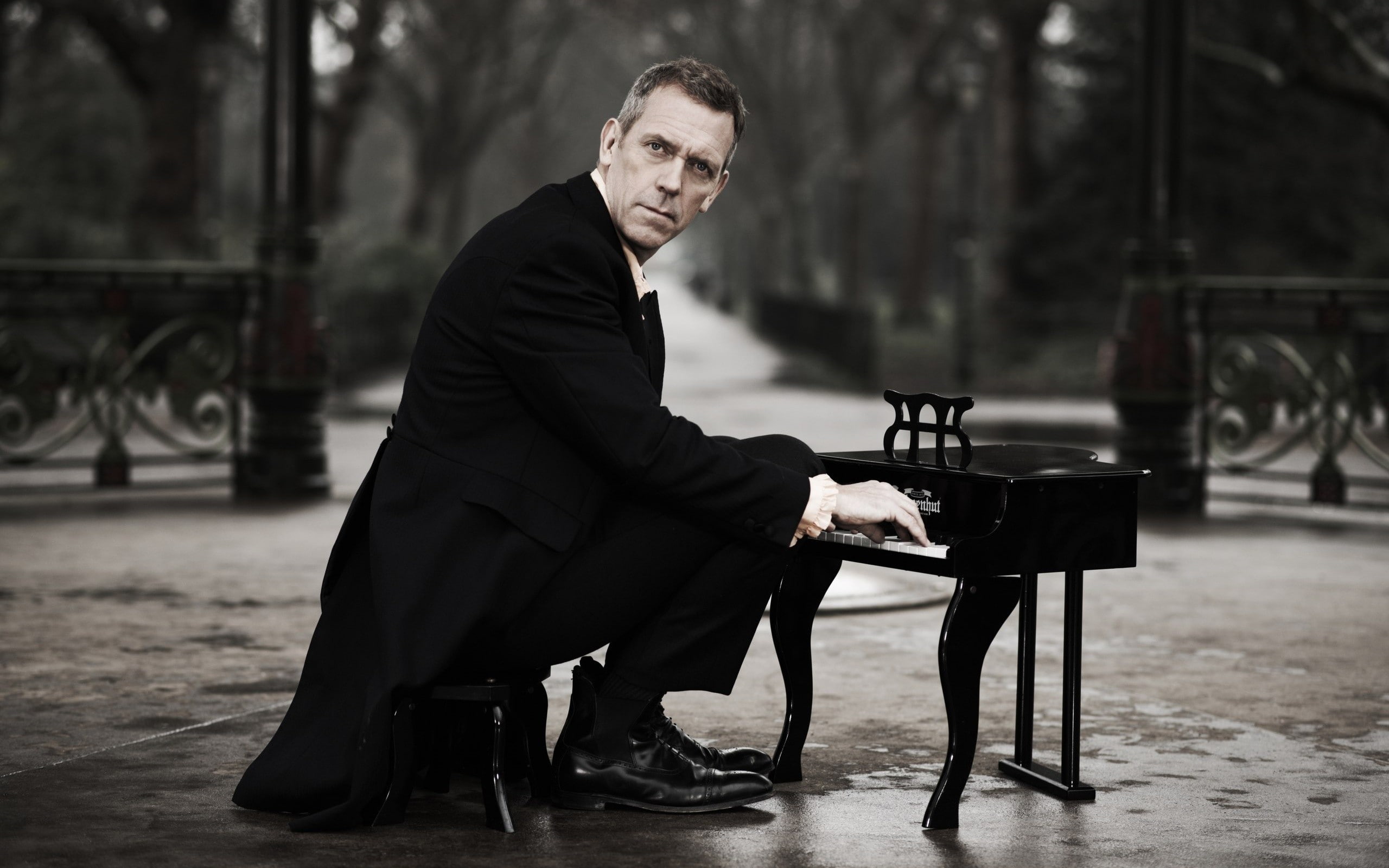 actor, chair, sitting, park, miniatures, 2K, humor, Hugh Laurie, men, trees, looking at viewer, piano, tuxedo, shoes, suits, HD Wallpaper